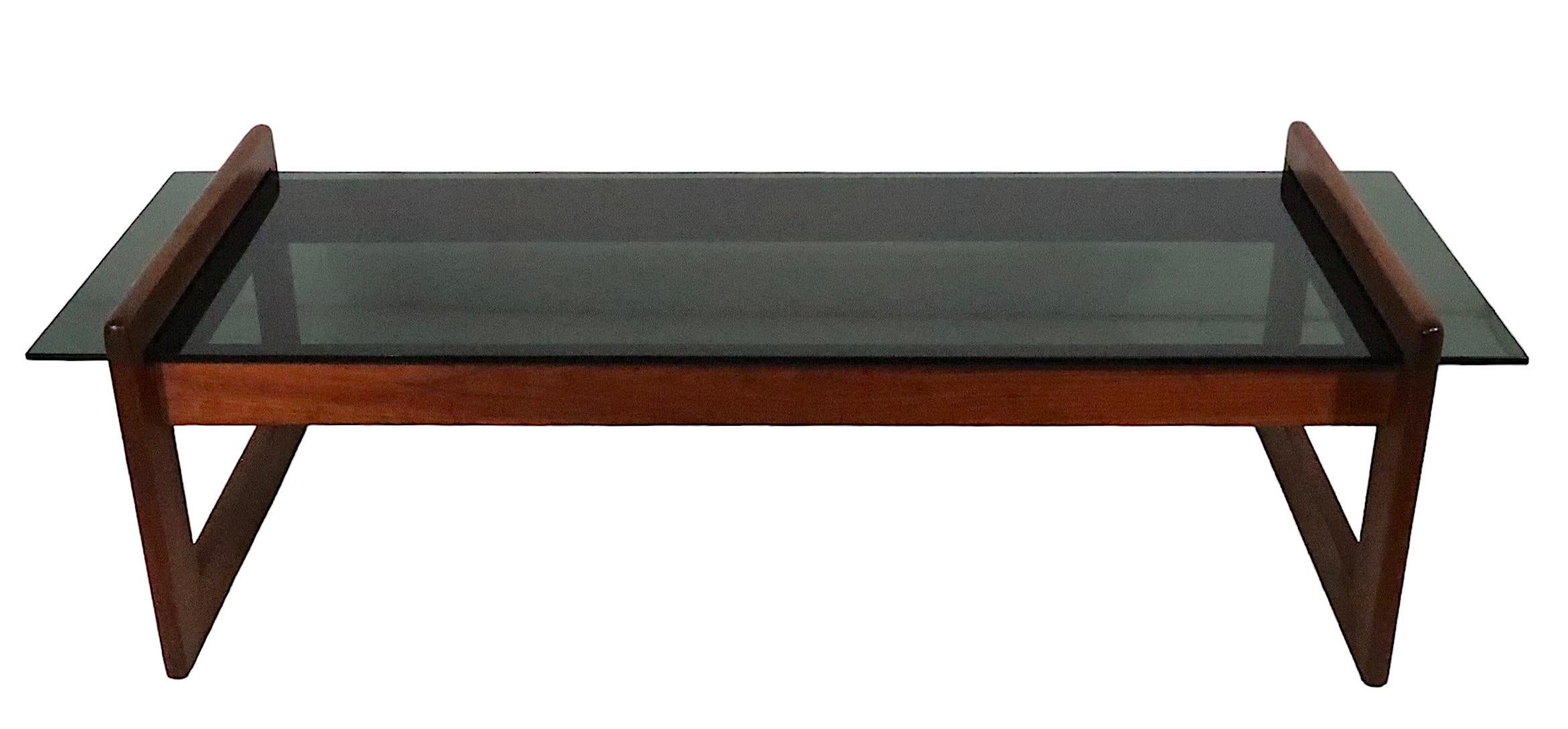 Exceptional Mid Century coffee table designed by Adrian Pearsall circa 1970's. The table features a thick tinted glass top, which slips into the architectural  walnut frame. This example is in excellent original condition, clean and ready to use,