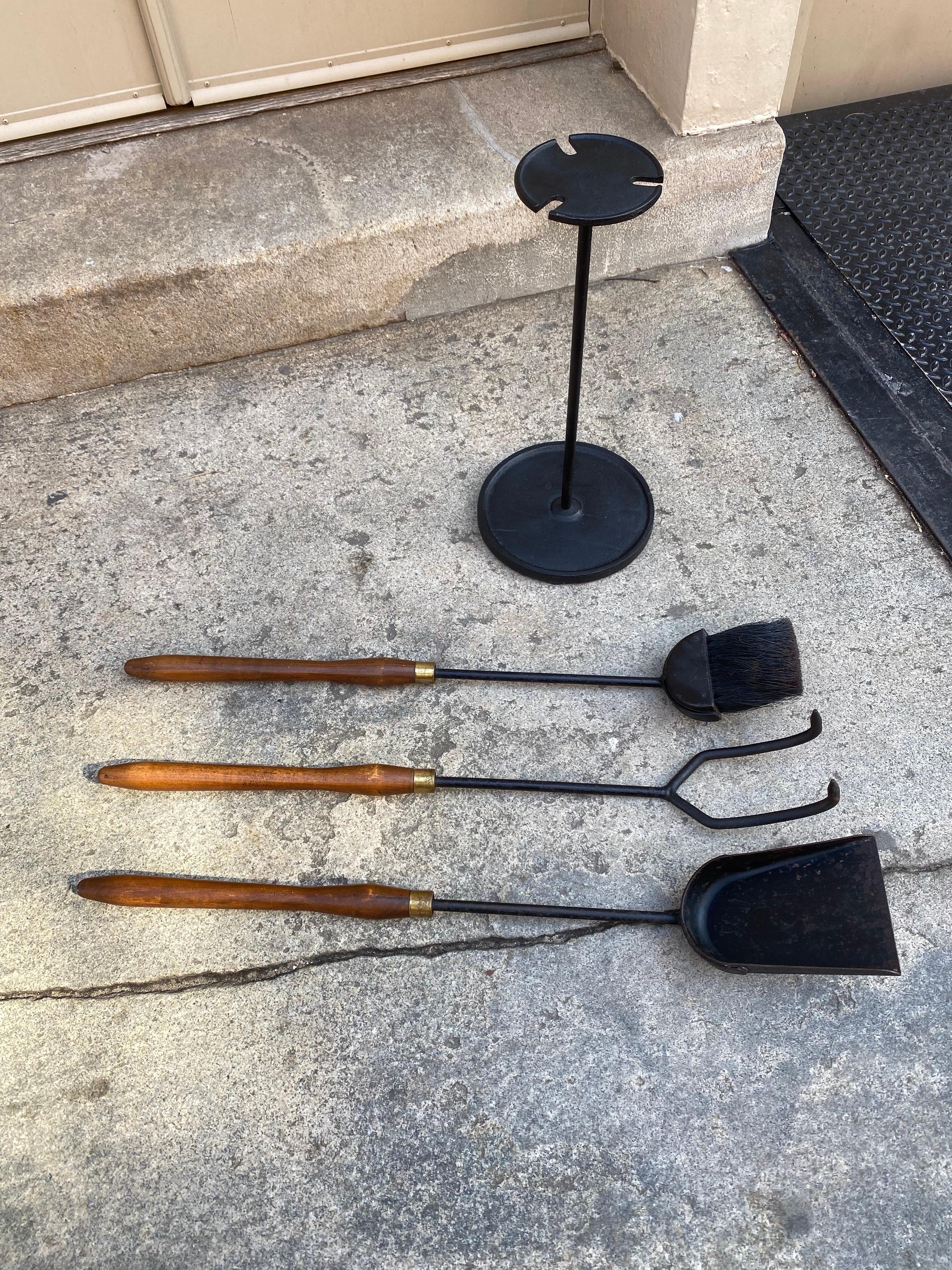 Mid century iron and wood 4 piece fireplace tool set. Nice sculpted wood elongated handles makes it easy to stay away from the heat! Sturdy metal stand cradles all three tools. Nice condition, with a stylist modern look!