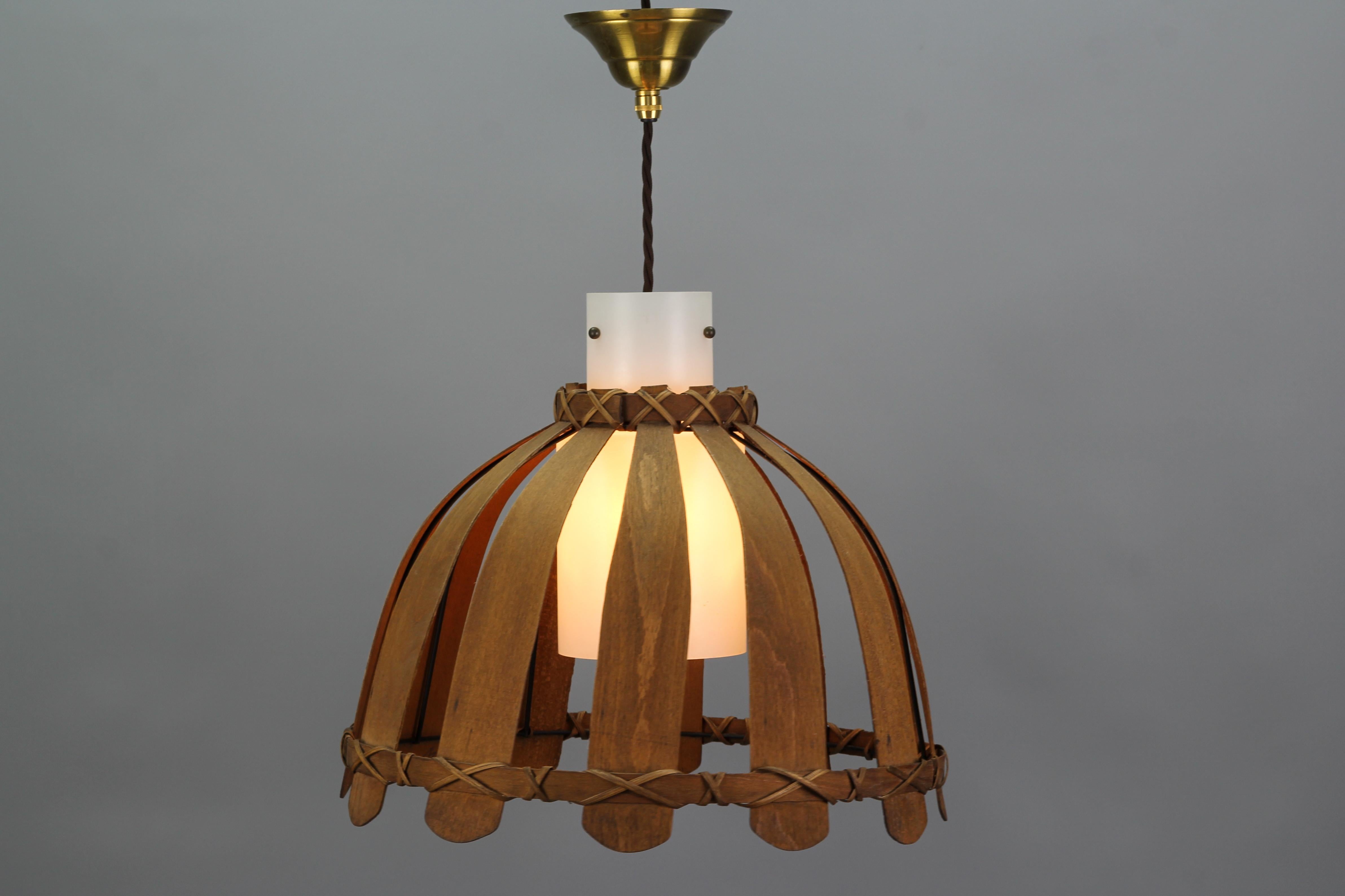 Beautiful and atmospheric vintage pendant light fixture, Germany, the 1970s. This pendant lamp features a wooden exterior and a white glass tube-shaped lampshade inside of the wooden frame. 
One new socket for E27 (E26) light bulb.
Adjustable