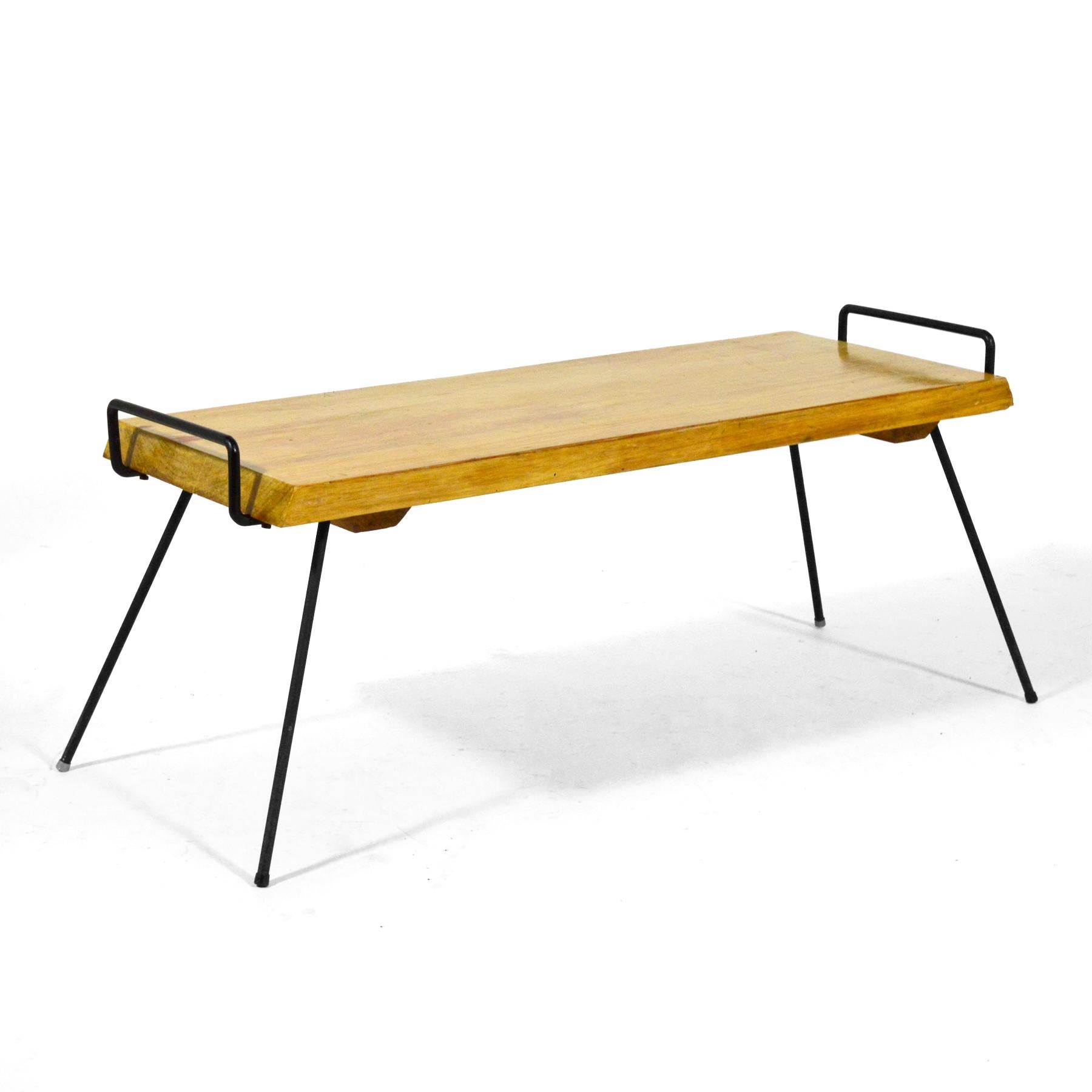 Cette pièce remarquable est composée d'un plateau en bois massif soutenu par des pieds en fer noir qui s'enroulent autour de la face inférieure pour créer des poignées à chaque extrémité. Avec une qualité à la fois folklorique, artisanale et