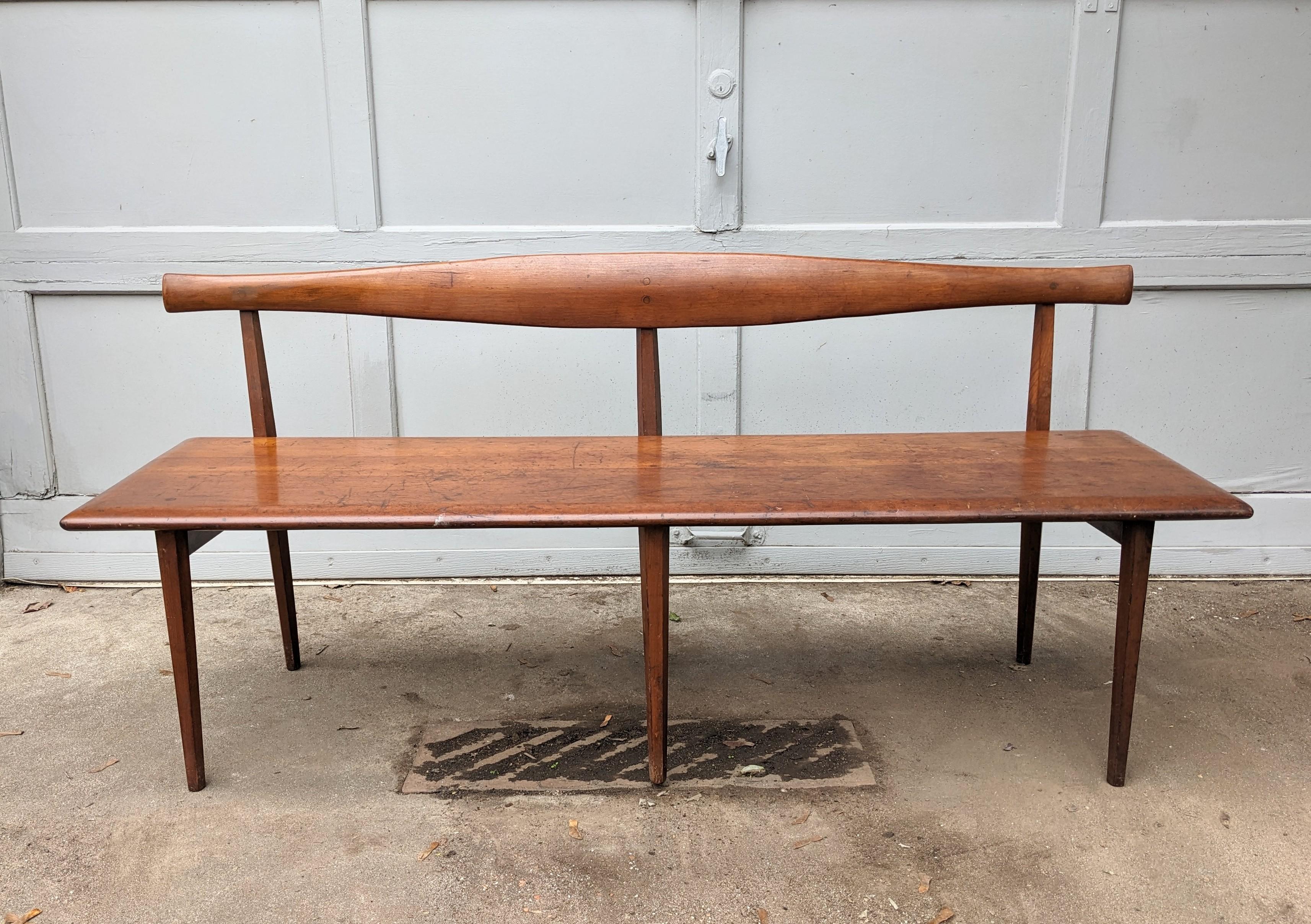 Elegant Mid Century Wood Bench by the Winchendon Furniture Co. with shaped lobed back rest on a simple, sleek design with faceted and tapered legs. Circa 1950's USA. American Design Foundation Medallion.