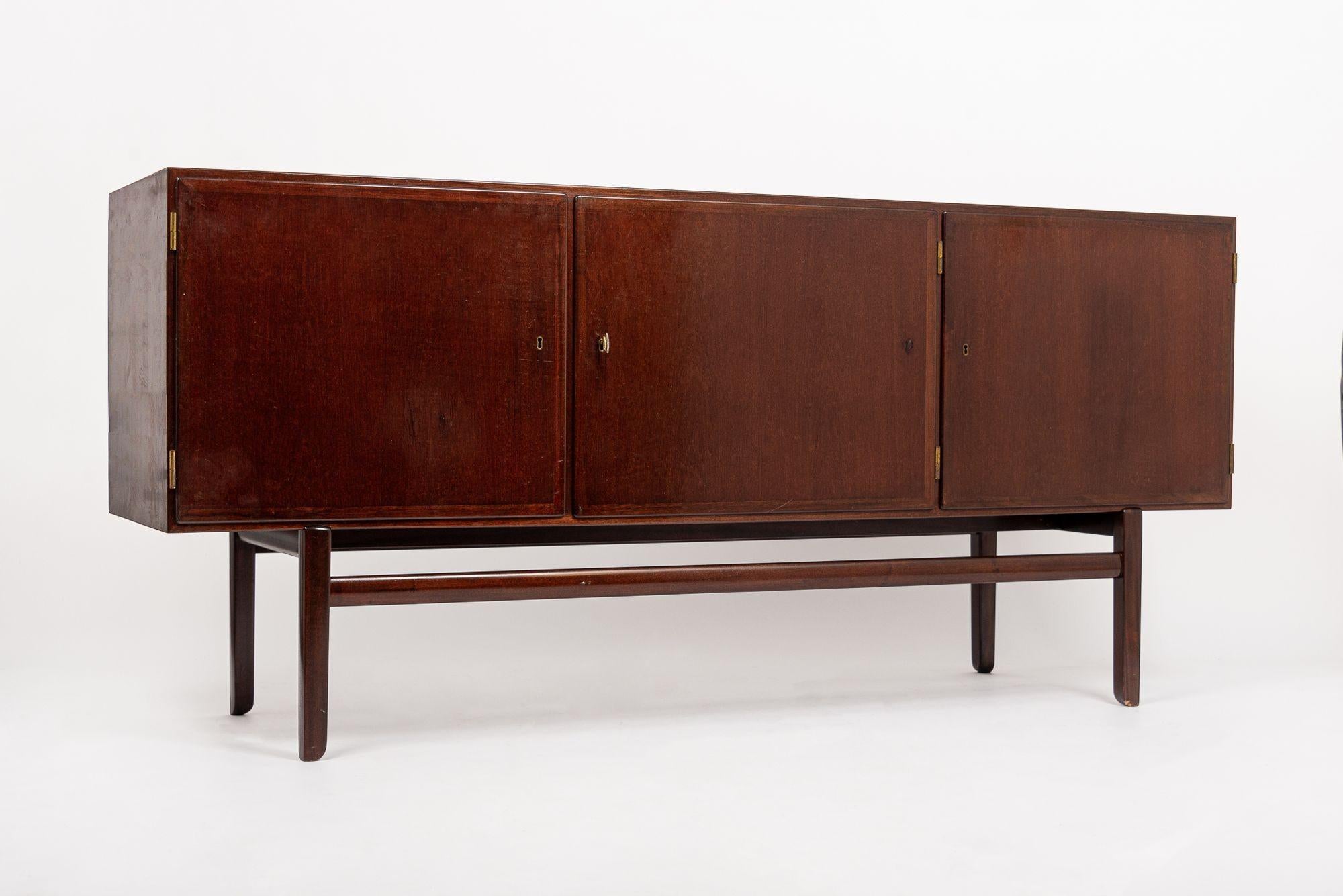 This iconic vintage mid century credenza modern credenza or sideboard cabinet designed by Ole Wanscher and produced by Poul Jeppesen Furniture was made in Denmark circa 1960. This “Rungstedlund” sideboard from the Rungstedlund dining collection was