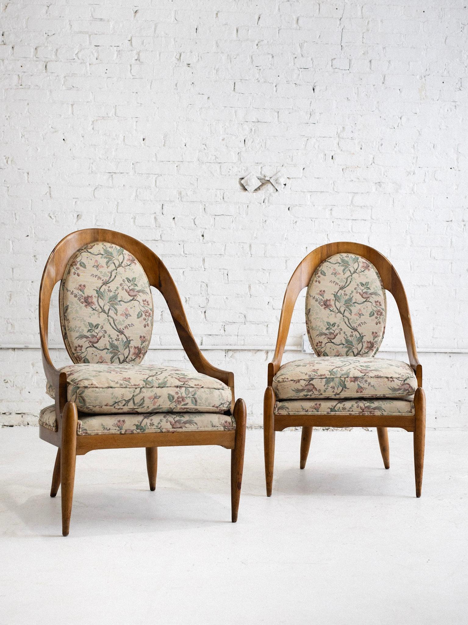 A pair of mid century spoon back chairs. Wood framed silhouette reminiscent of the Biedermeier style with tapered wood legs. Original floral upholstery.