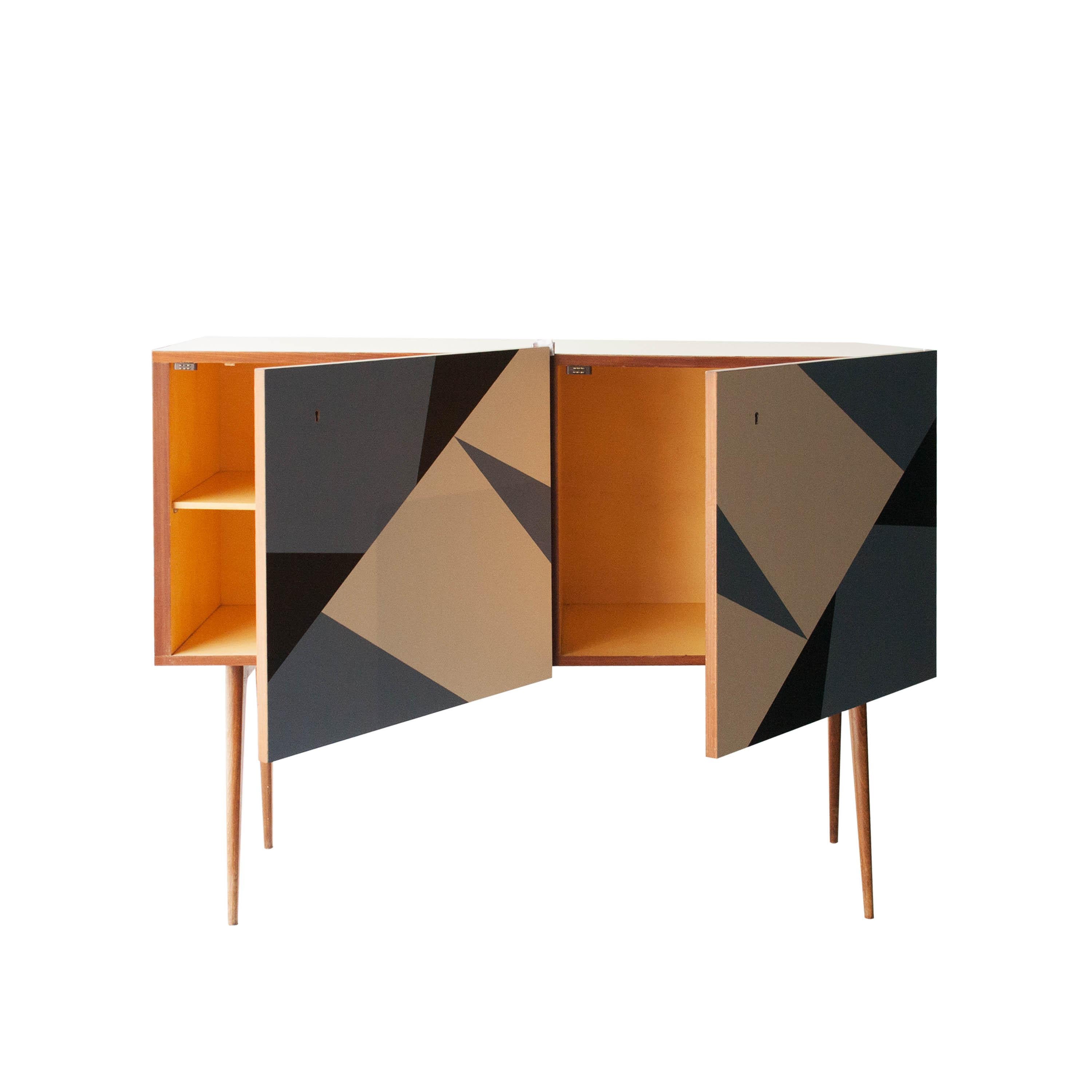 Sideboard with wooden structure and two doors. Top and doors coated in blue, white and black melamine whit geometric forms. Wooden conical legs.