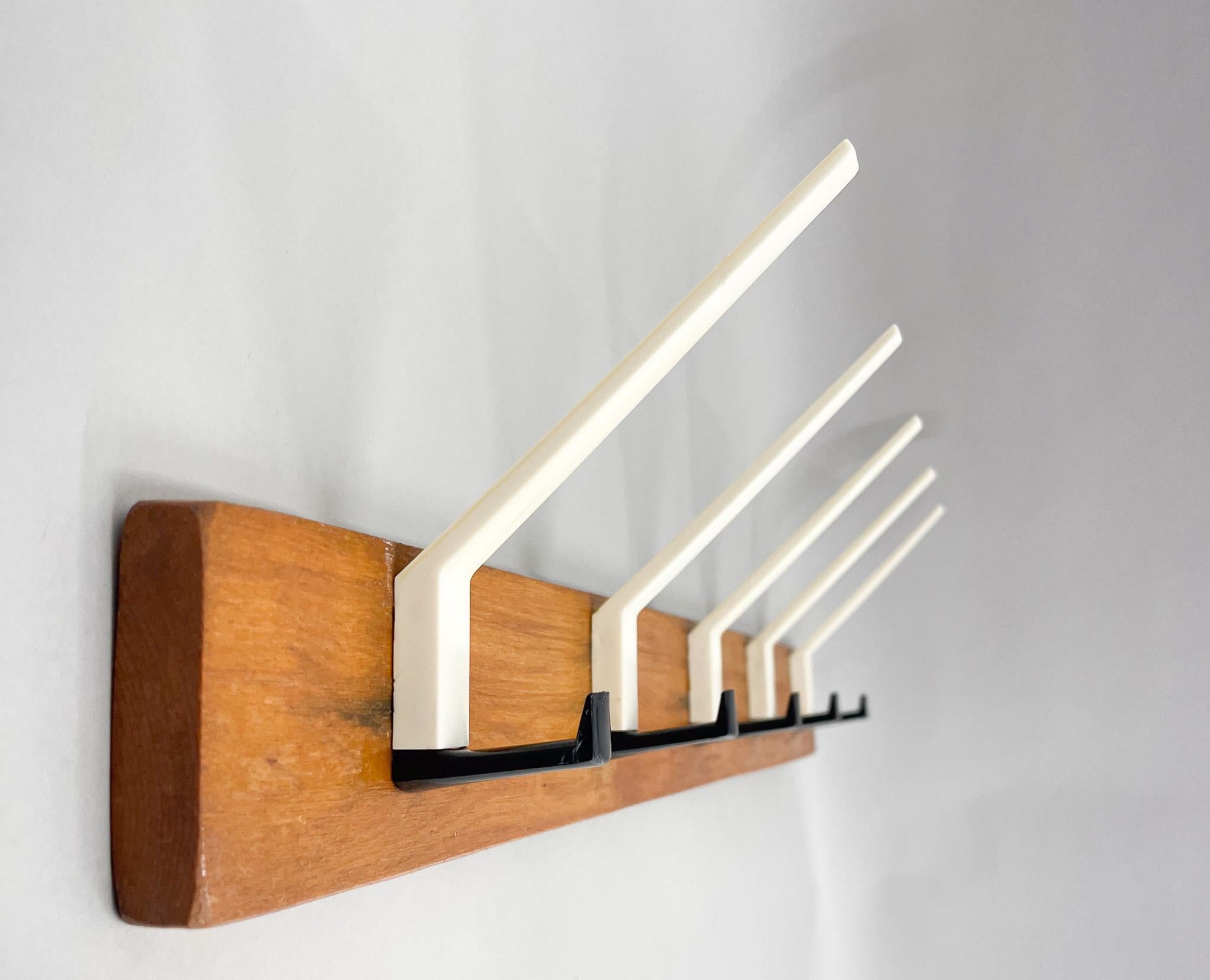 Vintage wooden wall coat rack with plastic hooks in black and white colours.