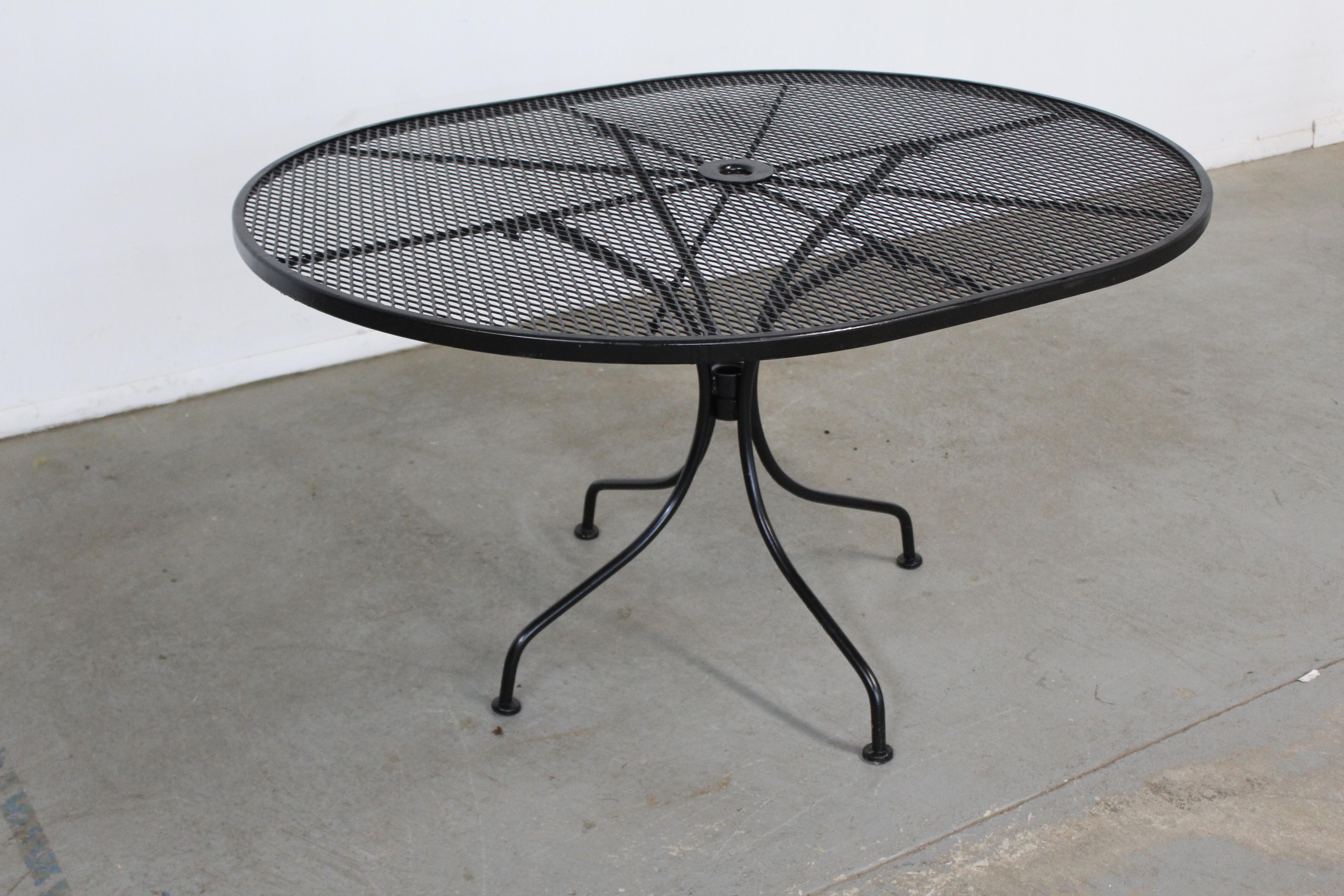 Mid-century outdoor iron woodard oval dining table 
Offered is a mid-century outdoor iron oval table. Features Black paint and woven wrought iron. The table is structurally sound in good condition and can accommodate up to 4 seats. Has been