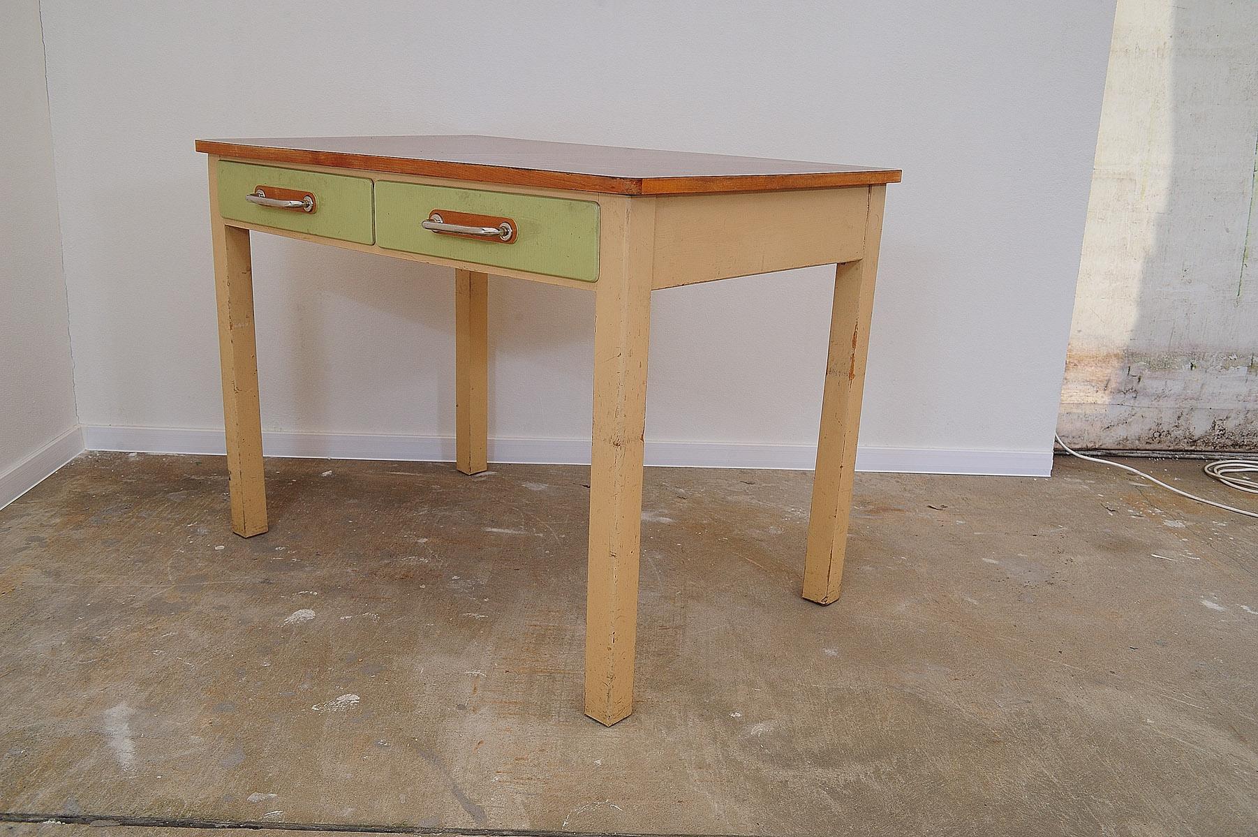 Mid century kitchen table with one drawer with a chrome handle as an interesting design element.

It was made in the former Czechoslovakia in the 1950´s. The table is made of wood and formica and painted in ivory and greenish color. Overall is in