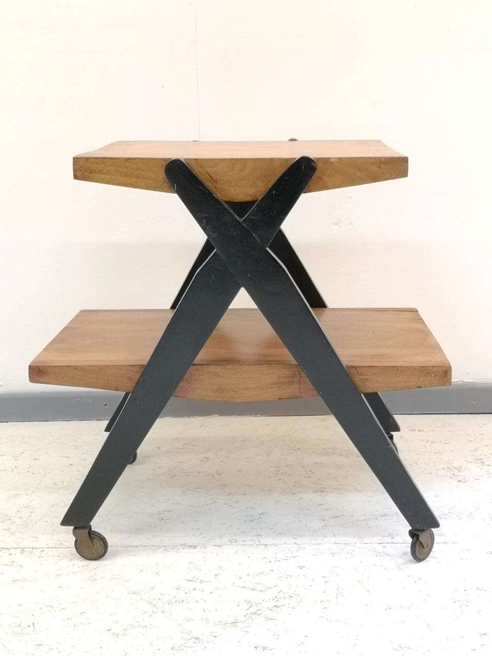 This walnut wood veneer bar cart was made in 1970s. It has painted black crossing legs, and runs on wheels. Generally good condition, but some scuffs and fading is visible on the veneer.