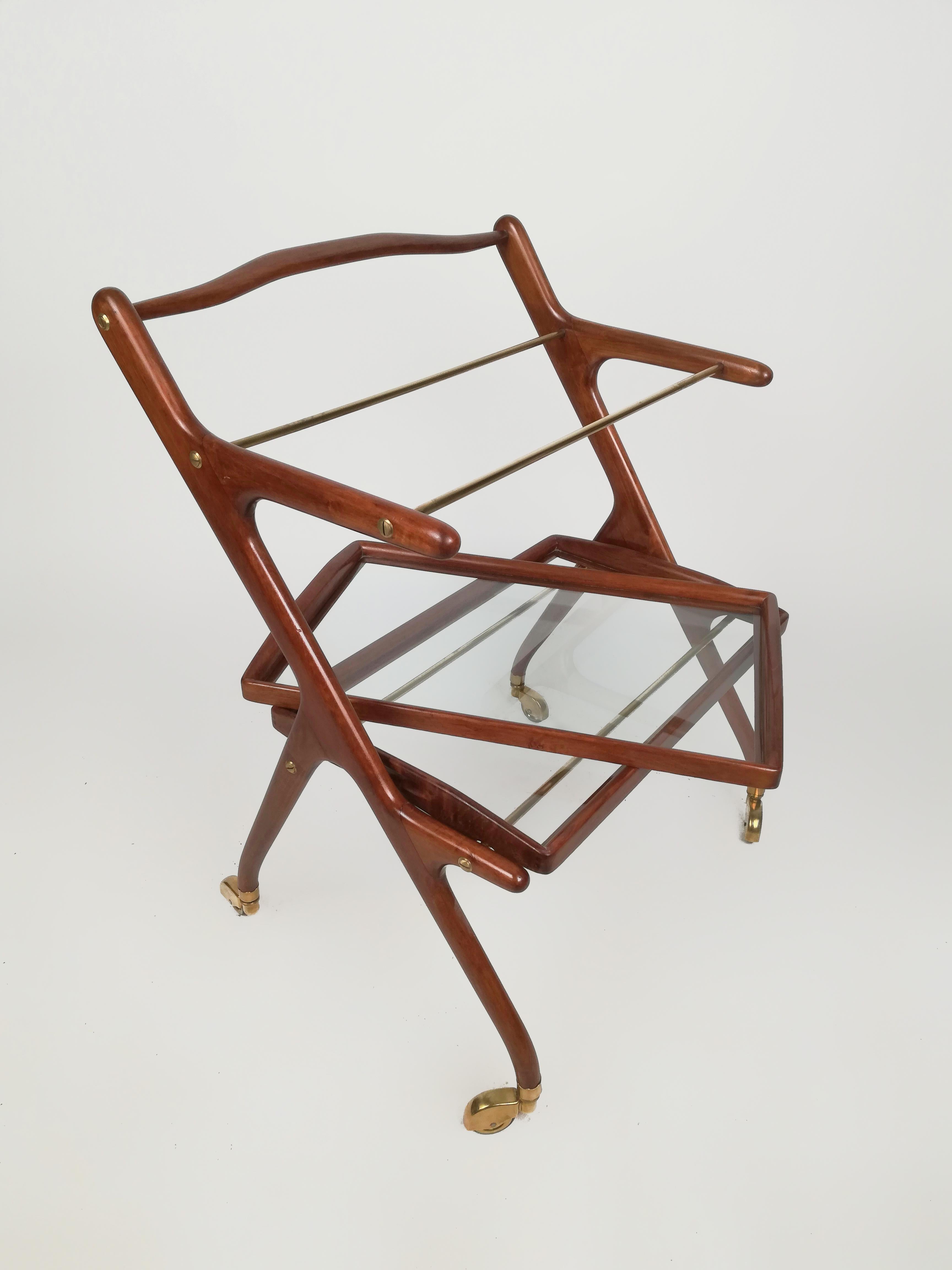 A trolley bar cart in the typical Italian style of the Mid-Century Modern Design.
The design of this Bar Trolley is attributed to Cesare Lacca for the famous Italian furniture company Cassina.
Inside the thin and light walnut-colored structure