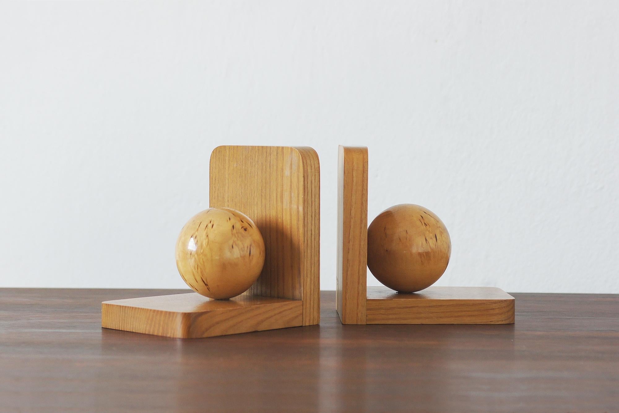 Una squisita coppia di reggilibri in stile Art Déco, realizzati in legno massiccio di quercia, presenta un audace design geometrico con scultorei accenti sferici. Le ricche venature del legno ne esaltano il calore e l'eleganza, rendendoli