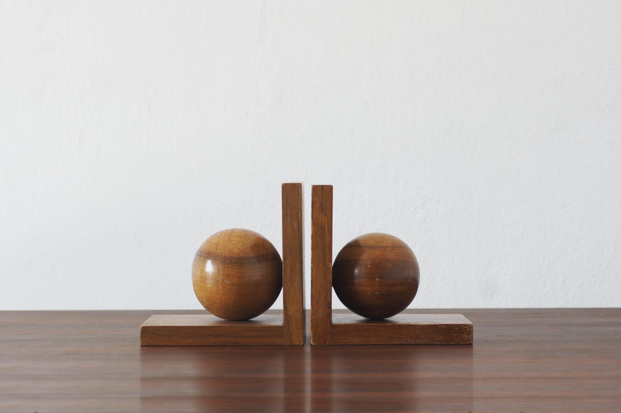 Una squisita coppia di reggilibri in stile Art Déco, realizzati in legno massiccio, presenta un audace design geometrico con scultorei accenti sferici. Le ricche venature del legno ne accentuano il calore e l'eleganza, rendendoli un'aggiunta senza