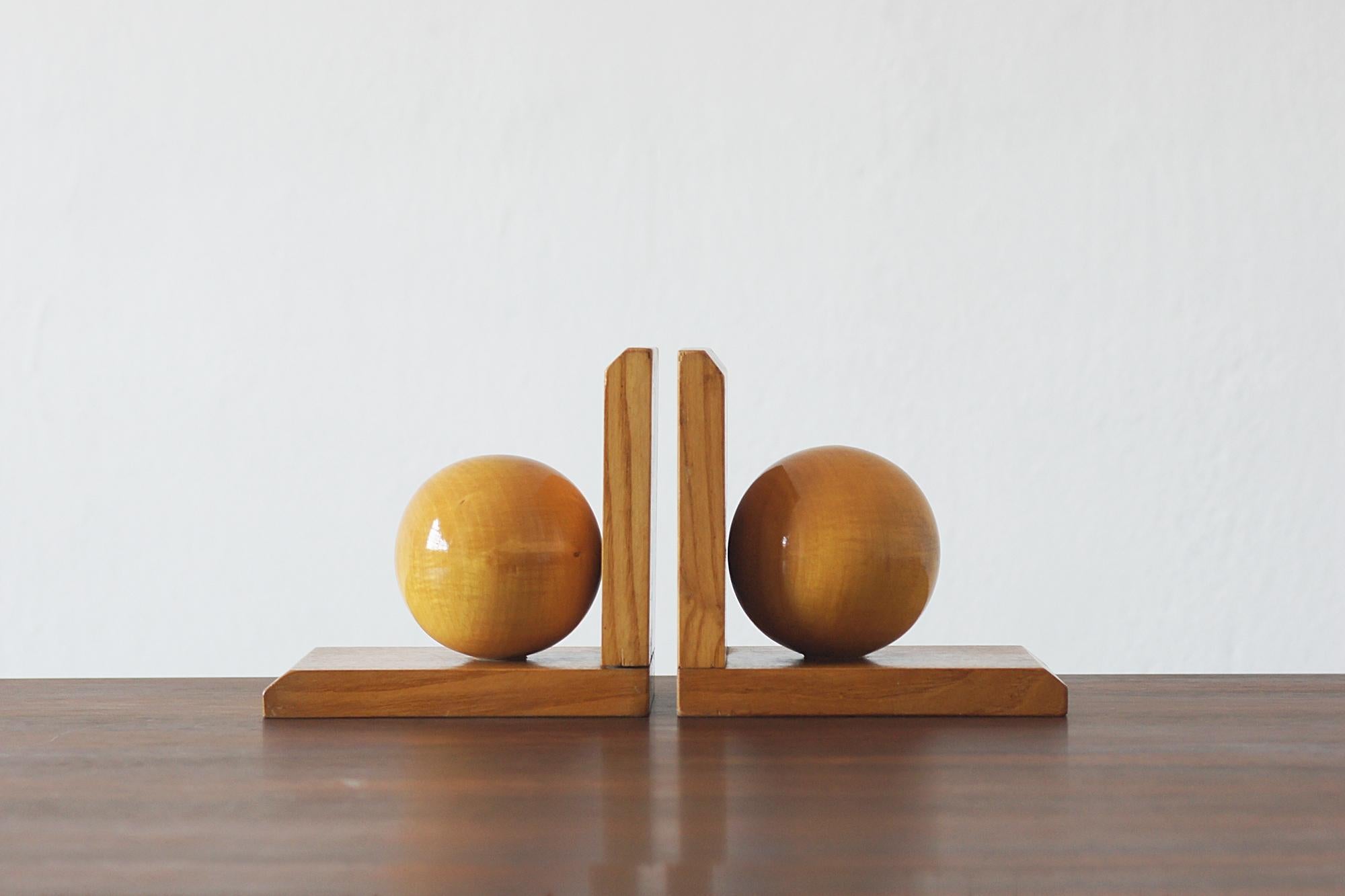 An exquisite pair of Art Deco style bookends, crafted from solid wood , showcases a bold geometric design with sculptural spherical accents. The rich grain of the wood accentuates their warmth and elegance, making them a timeless addition to any
