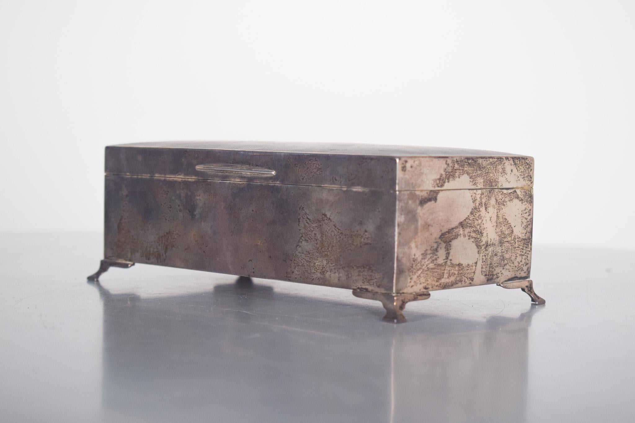Boîte en bois plaquée argent. La partie extérieure, en argent foncé dû à l'oxydation naturelle, donne du charme à la pièce et met en valeur son authenticité et son histoire. La boîte repose sur quatre petits pieds décorés, qui surélèvent la base et