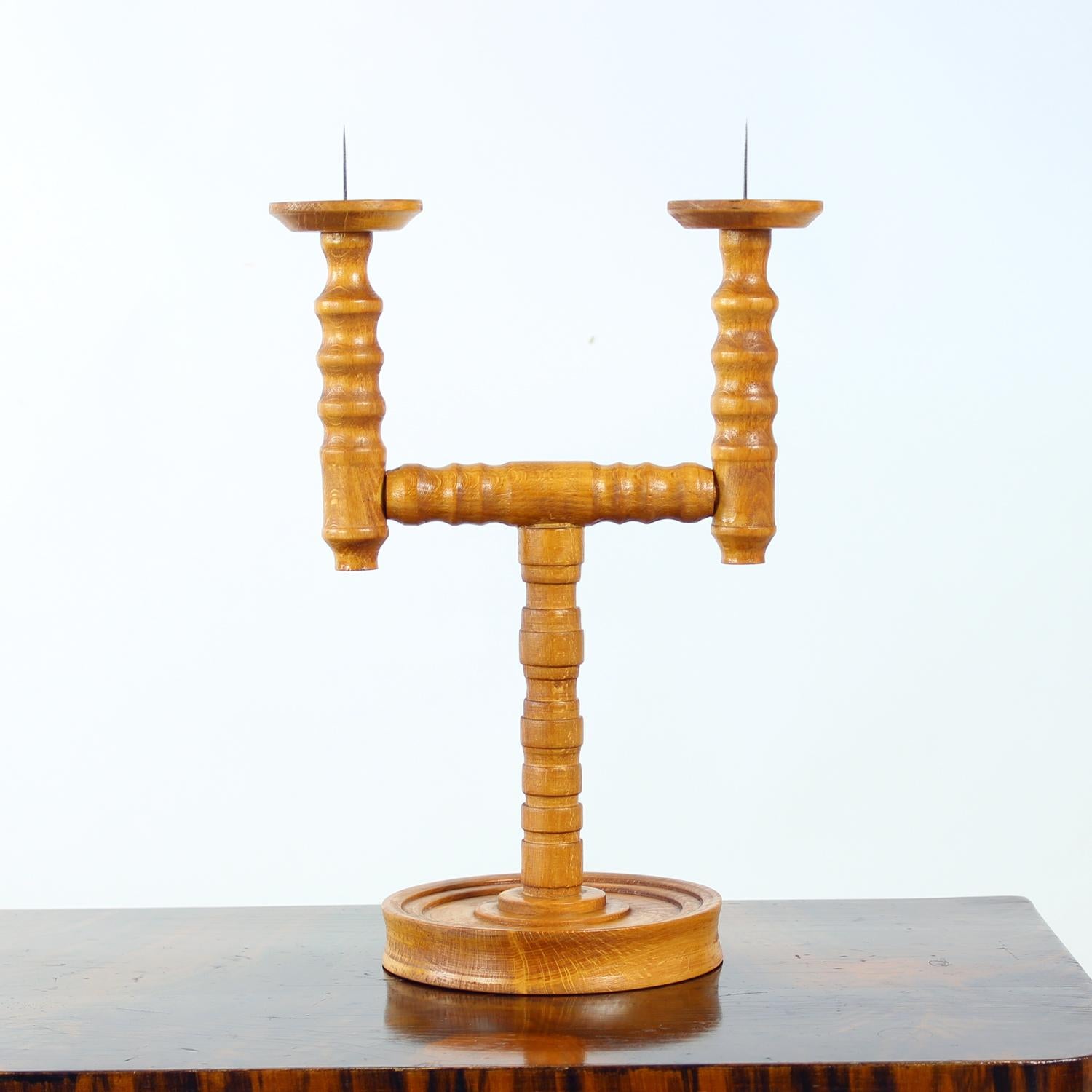 Un hermoso candelabro tallado de mediados de siglo fabricado en Checoslovaquia en la década de 1950. Fabricada en madera maciza, esta elegante pieza sostiene dos velas y muestra finos detalles tallados a mano con una silueta escultural típica de la