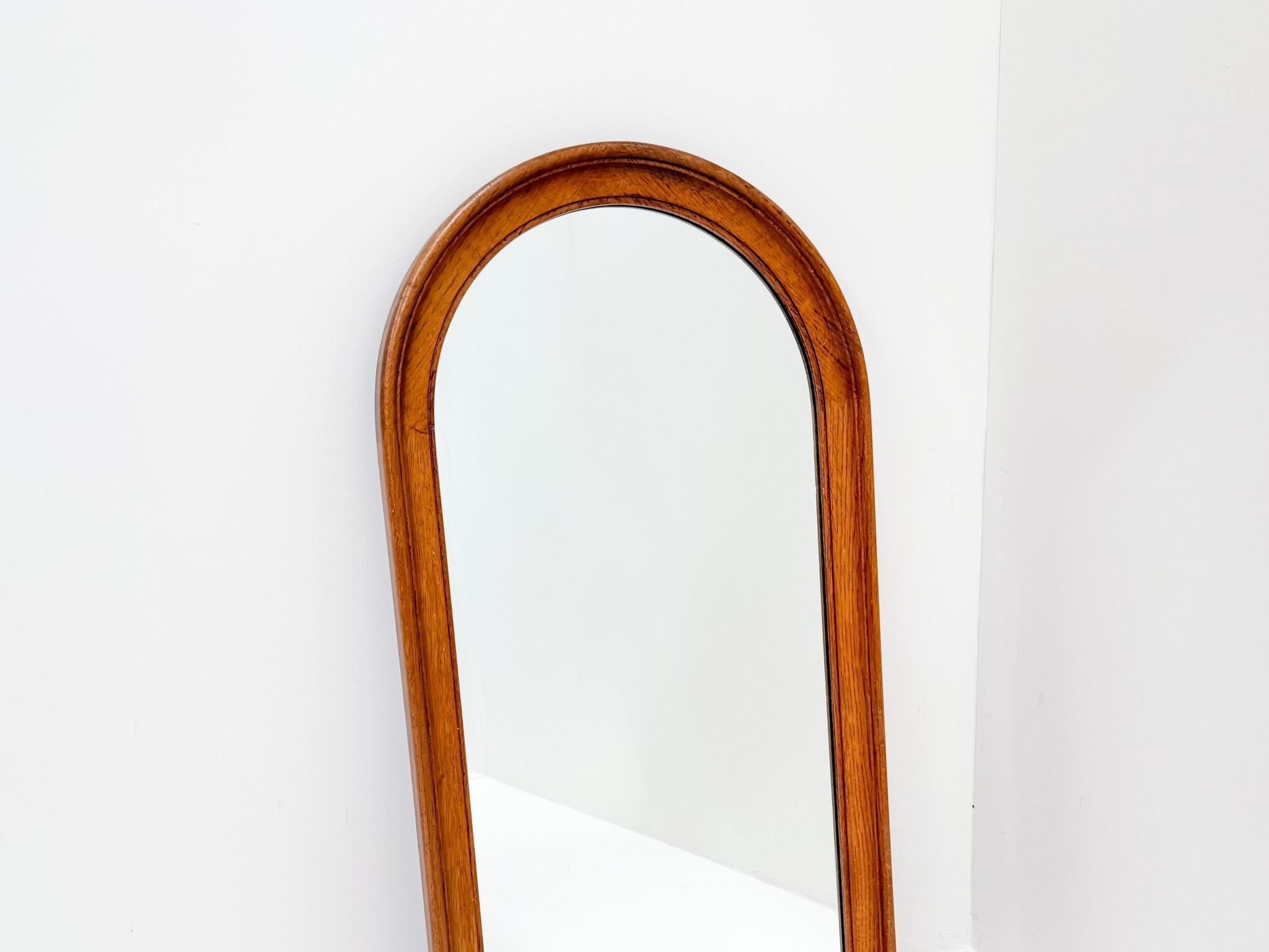 Miroir mural vintage du milieu du siècle avec un cadre en bois massif et un élégant sommet arrondi. Le bois clair lui confère un aspect naturel et chaleureux, s'adaptant parfaitement aux intérieurs scandinaves ou minimalistes. Datant probablement