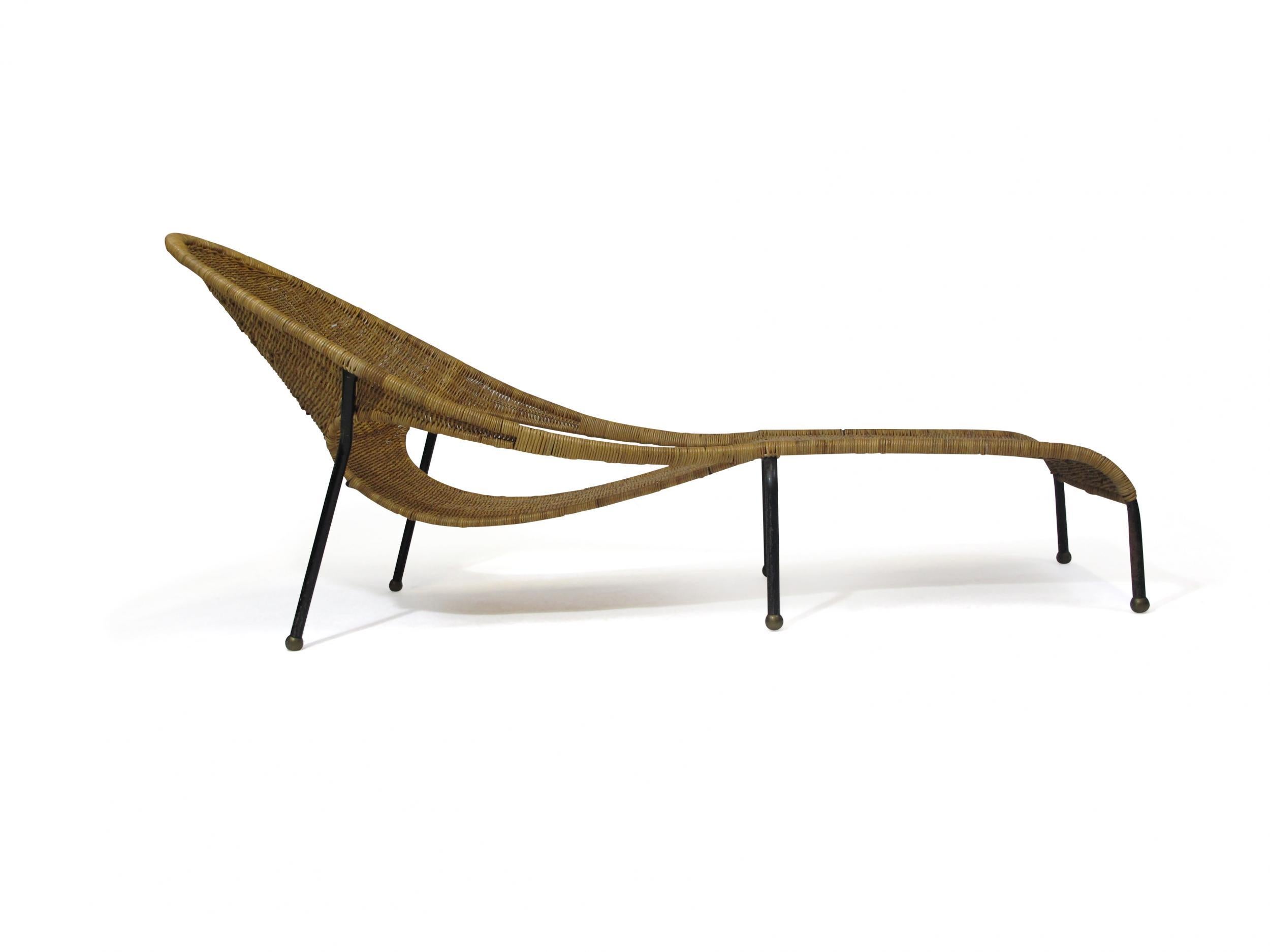 Midcentury wicker chaise lounge chair crafted of metal frame with brass ball feet, and woven wicker.
 