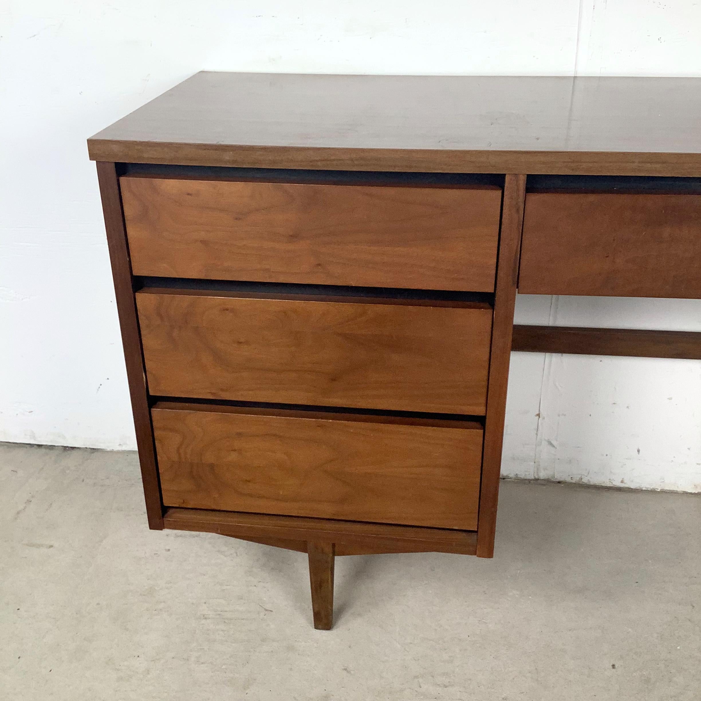 Presentamos un escritorio de mediados de siglo de Stanley Furniture, fabricado en chapa de nogal con un práctico tablero laminado de imitación madera. Esta pieza, que data de los años sesenta, ejemplifica las líneas limpias y la cuidada