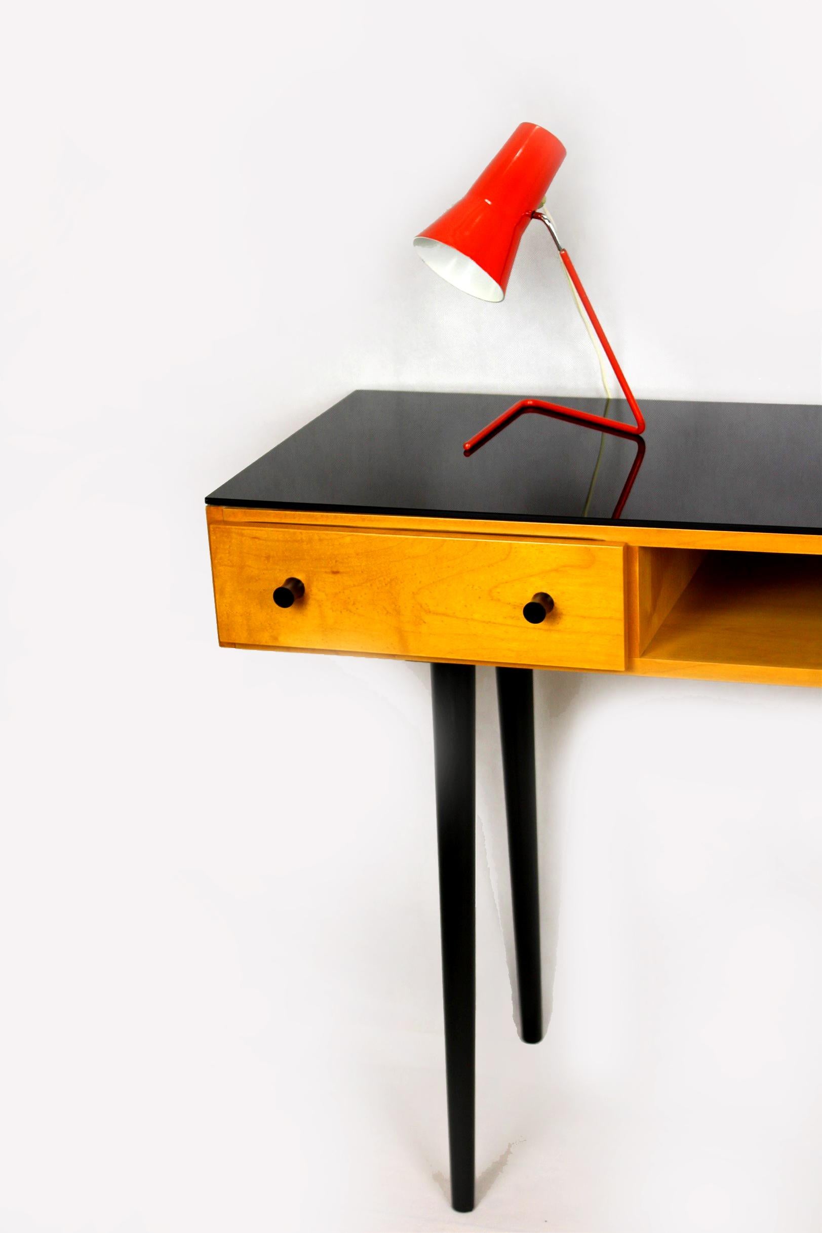 Mid-century writing desk which can also be used as a console table. Manufactured by UP Zavody Bucovice in former Czechoslovakia during the 1960s. Features two drawers and original black glass on the top.
 