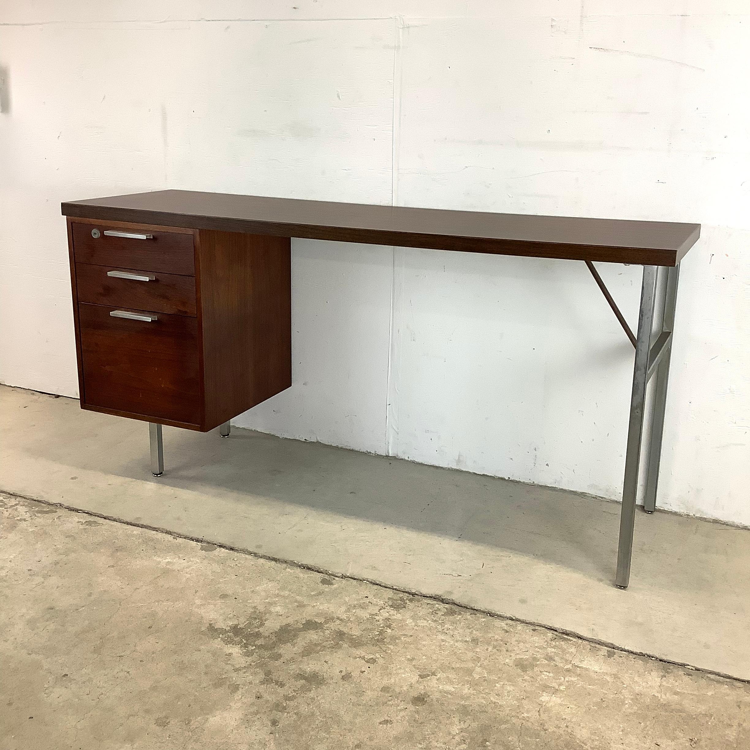 This unique midcentury writing desk is long and narrow with a durable laminate top and sturdy metal frames. Three drawer configuration includes plastic tray inserts and lower filing cabinet. The wide open space below the desktop allows for ease of