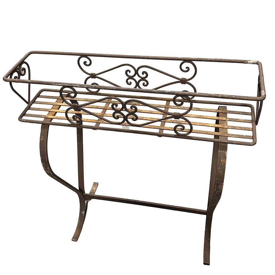Mid-century era wrought scrolling trestle style elevated planter stand with aged with a beautiful 70-year-old patina. The stand features a classic design with a square box shape on curved half-glass legs with scrolling detailing along each side. The