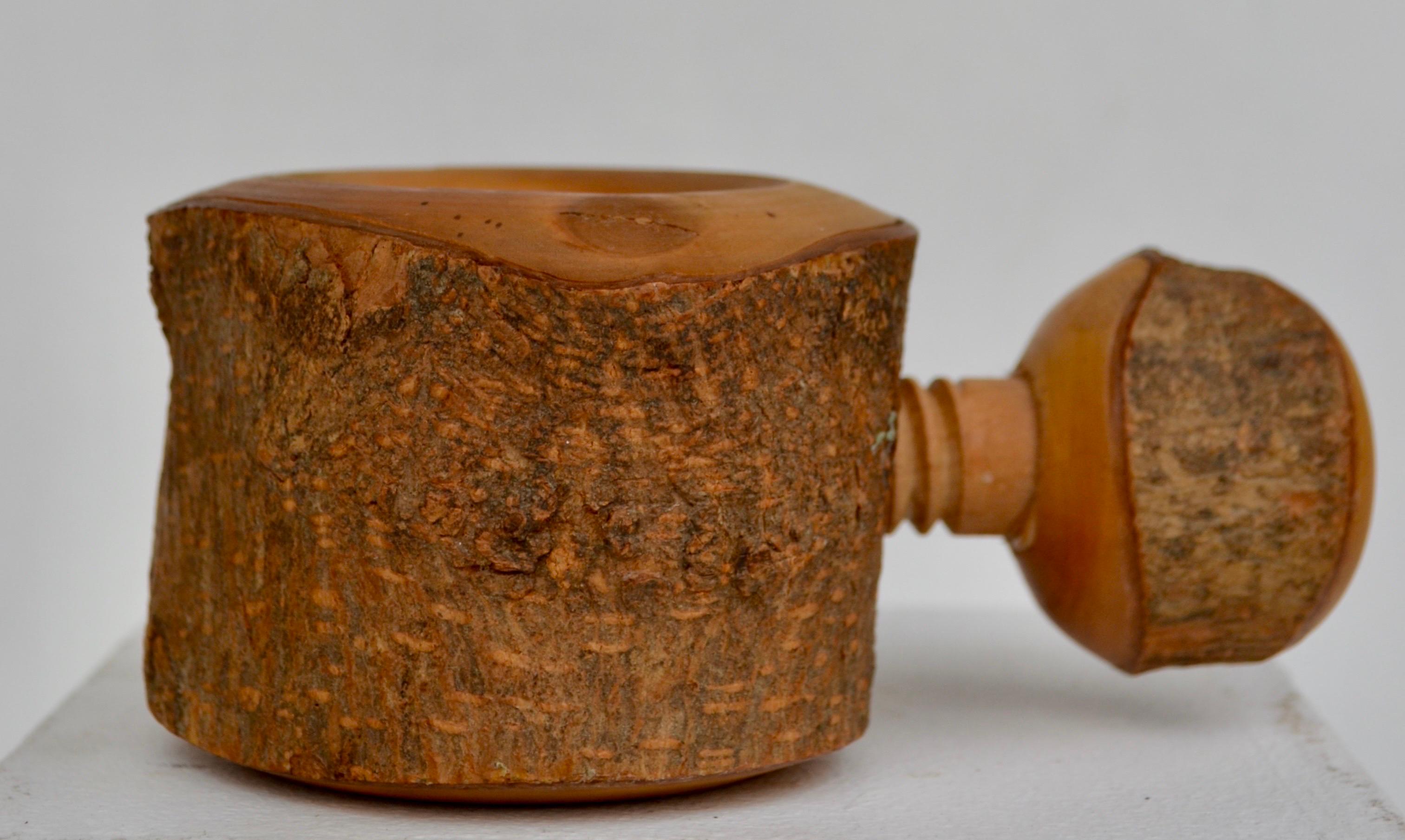 Incantevole schiaccianoci di arte popolare realizzato a mano da un tronco di legno massiccio, splendidamente intagliato e scavato preservando la corteccia naturale. Il meccanismo a vite, anch'esso interamente realizzato in legno, mette in mostra