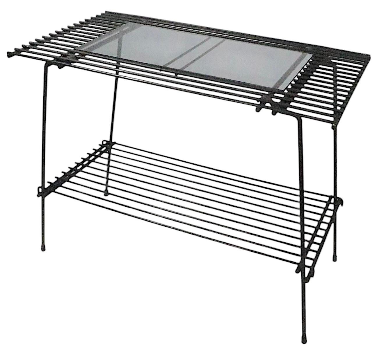 Table d'appoint architecturale en fer forgé et verre teinté à deux niveaux, support de plantes, vers 1950/60. Cette table inhabituelle présente des tiges métalliques répétitives, soudées à un cadre rectangulaire. L'étagère supérieure est dotée d'un