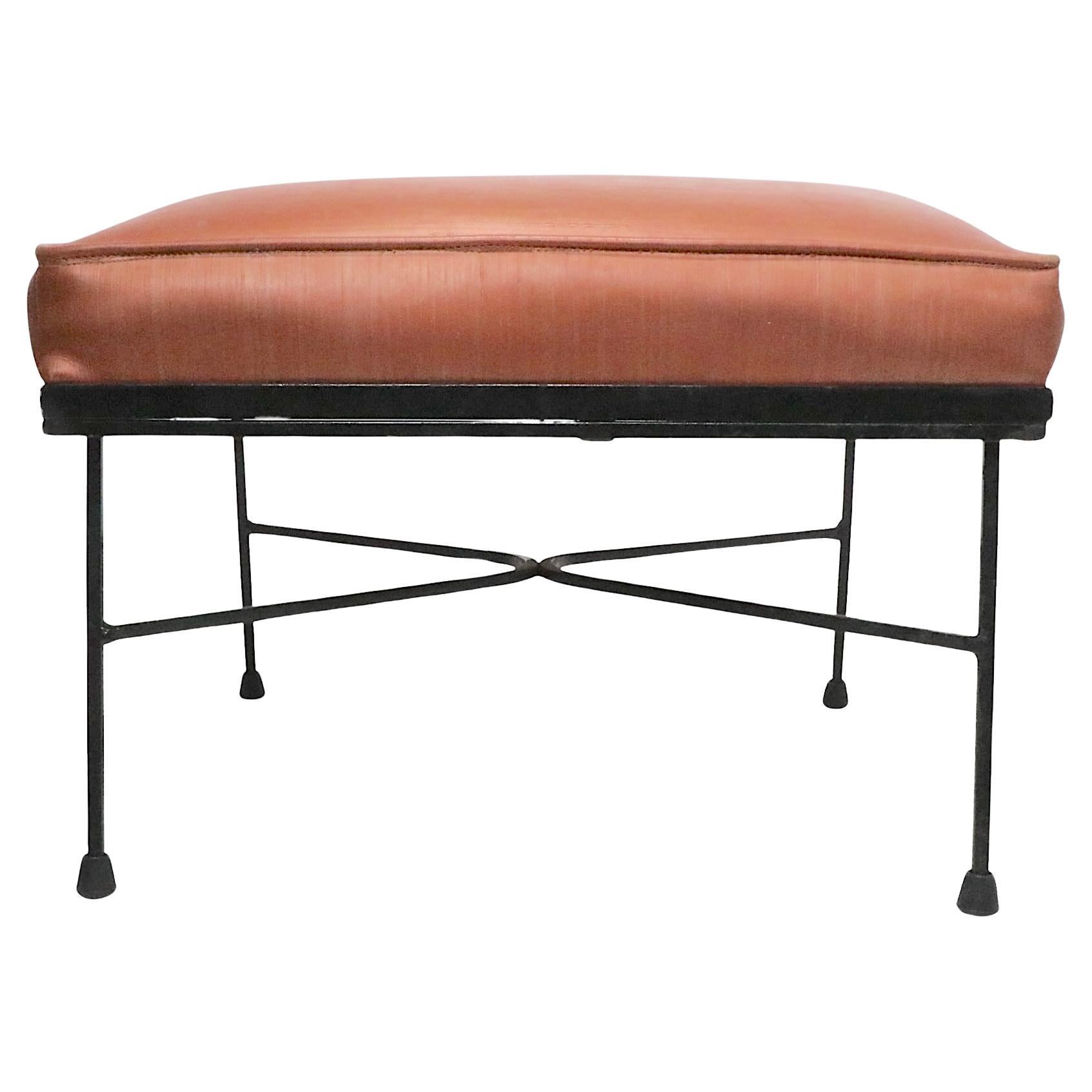 Chic Mid Century footstool, ottoman having a vinyl upholstered pad top, mounted on a wrought iron base. The stool is in very good, clean, ready to use condition. The ottoman is solid, sturdy and solid, the rubber boot glides are replacement pieces. 