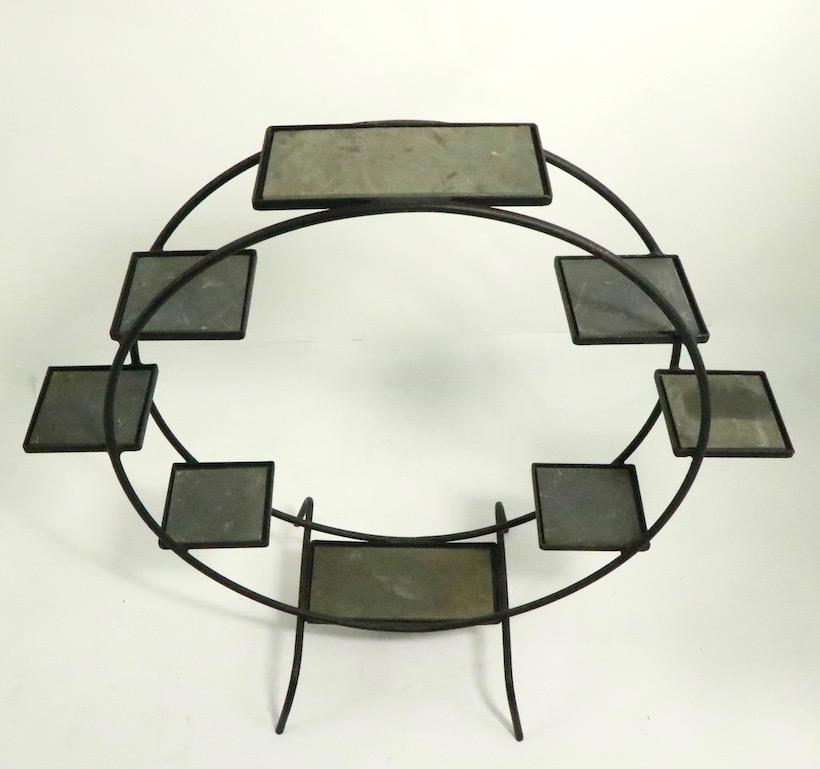 Circular wrought iron plant stand having 8 shelves, each with a slate stone insert surface. Two shelves are larger 12 x 6 (top and bottom ) the remaining six are 6 x 6 inches. Architectural form reminiscent of a Ferris Wheel, great for a patio, or