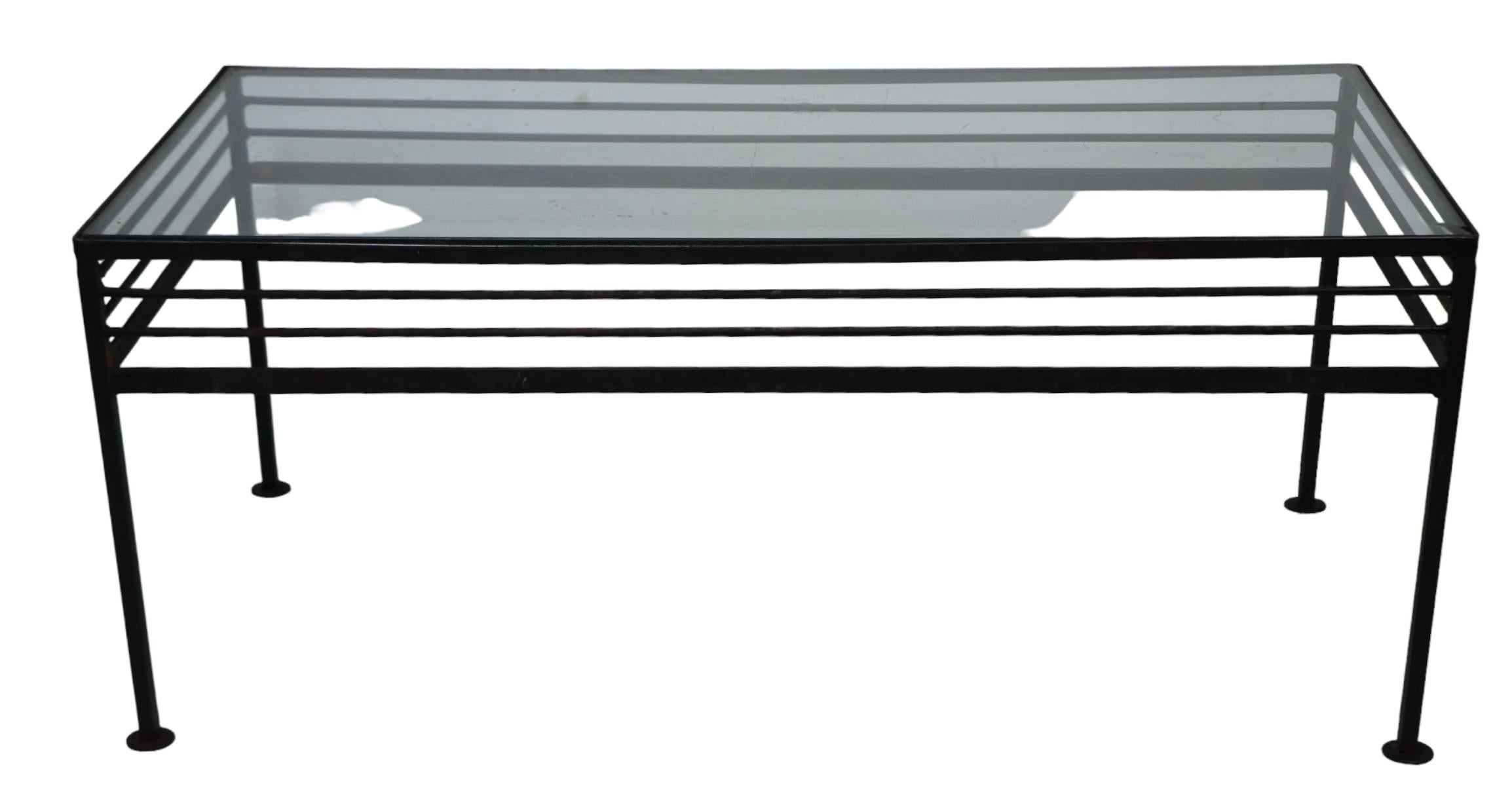 Tavolino architettonico in ferro battuto, attribuito a The Woodard Furniture Company, nello stile di Avard, Salterini, McCobb etc. Il tavolo presenta aste orizzontali ripetute che accentuano la forma rettangolare minimalista. Il tavolo ha il suo