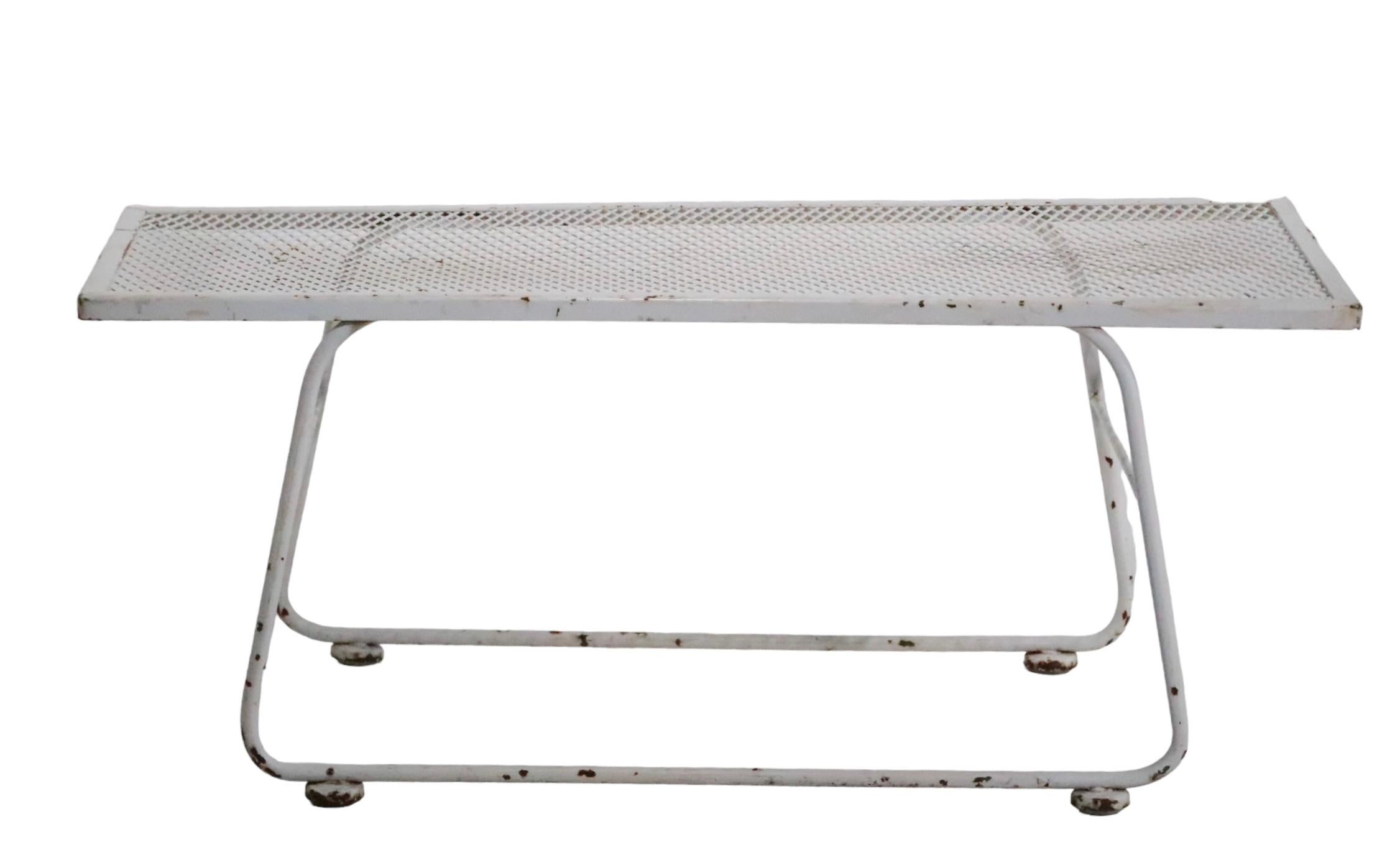 Mid Century wrought iron and metal mesh garden, patio, poolside table, attributed to Woodard. The table features rectangular metal mesh top, on a continuous wrought iron leg base. The table is in original white paint finish, which shows wear, normal