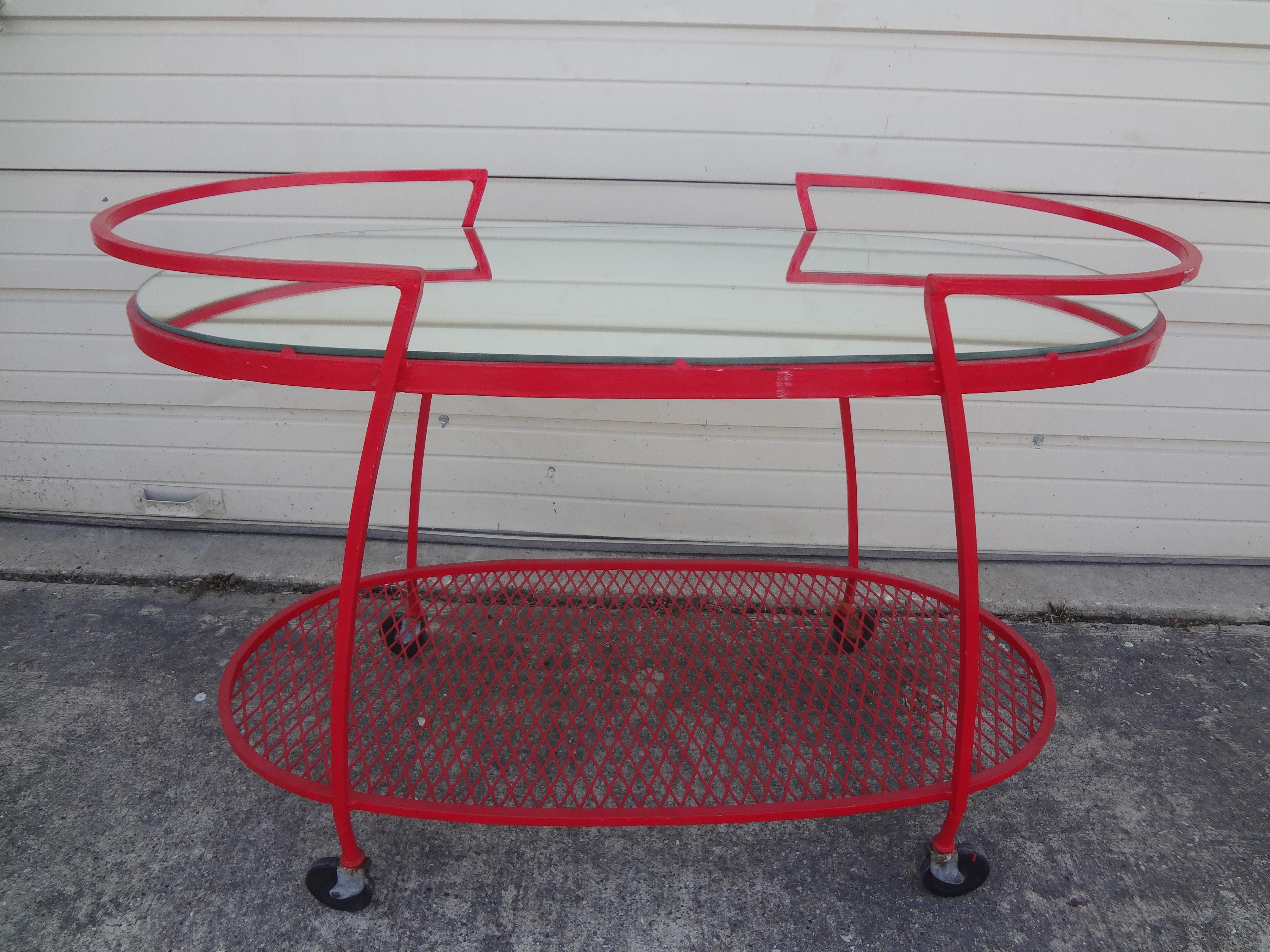 Midcentury wrought iron bar cart or serving cart by Woodard. This versatile bar cart was designed by Russell Woodard for Woodard Furniture Company.
This stunning large iron serving cart, drinks cart, bar cart or serving trolley in a stunning red