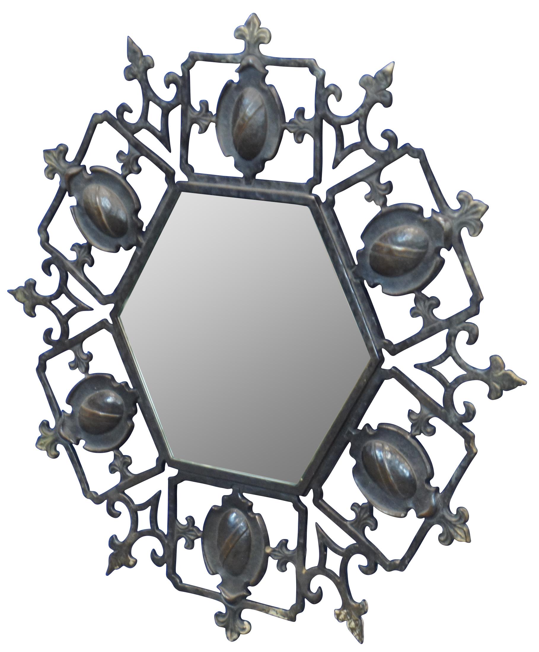 Mid century wrought iron medieval or Spanish Revival wall mirror with a hexagonal / circular / starburst / sunburst shape surrounded by a pierced / reticulated design of heraldic shields and fleur de lis. Measure: 17