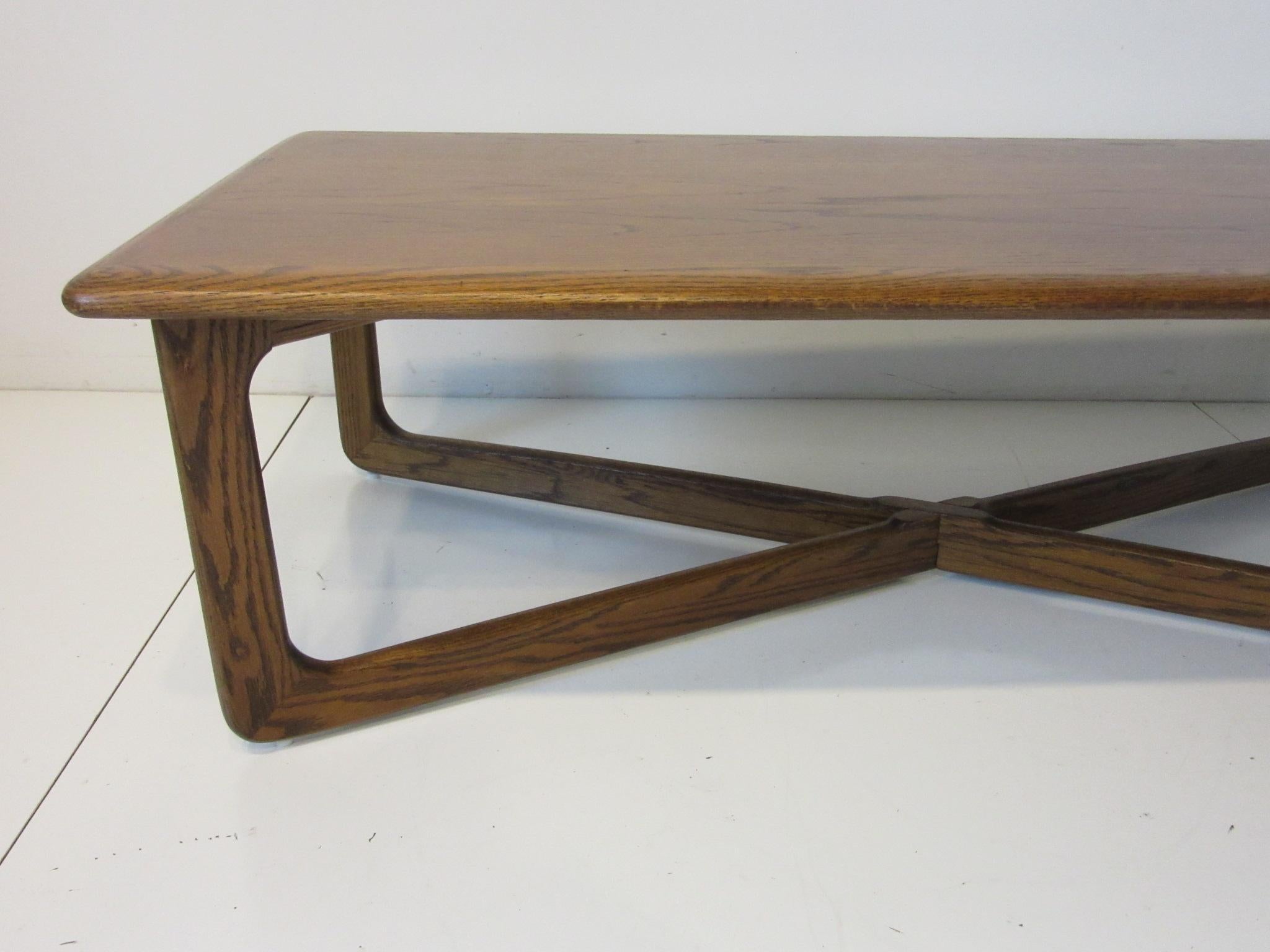 A medium walnut finished coffee table with X base having wonderful graining to the top and rounded edges. Well constructed and retains the branding mark to the bottom, manufactured by the Lane furniture company from their Perception collection.