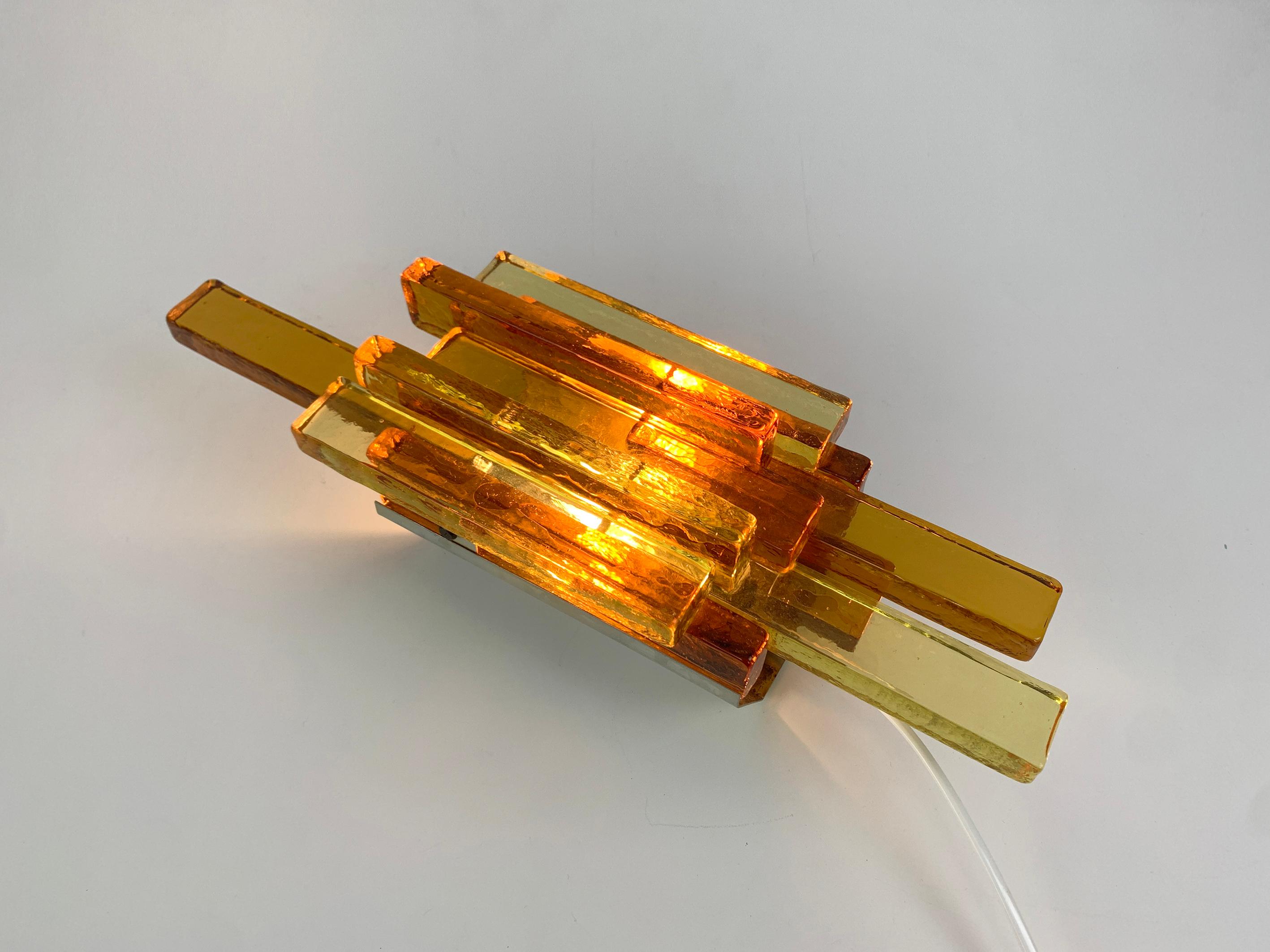 Wall lamp by Svend Aage Holm Sørensen.
Assembly of thick yellow, amber and orange glass bricks which give an amazing light effect.
The glass composition is attached to a wall fixing made of sheet metal.
Svend Aage Holm Sørensen (1913-2004) was a