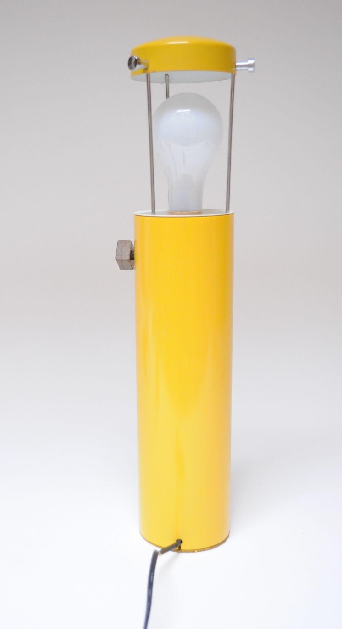 Unique column/tube table lamp in attractive yellow metal and plastic (top is enameled metal, while the column is yellow plastic) with a wooden cube three-way switch, which, when used with a three-way bulb, allows for three illumination settings