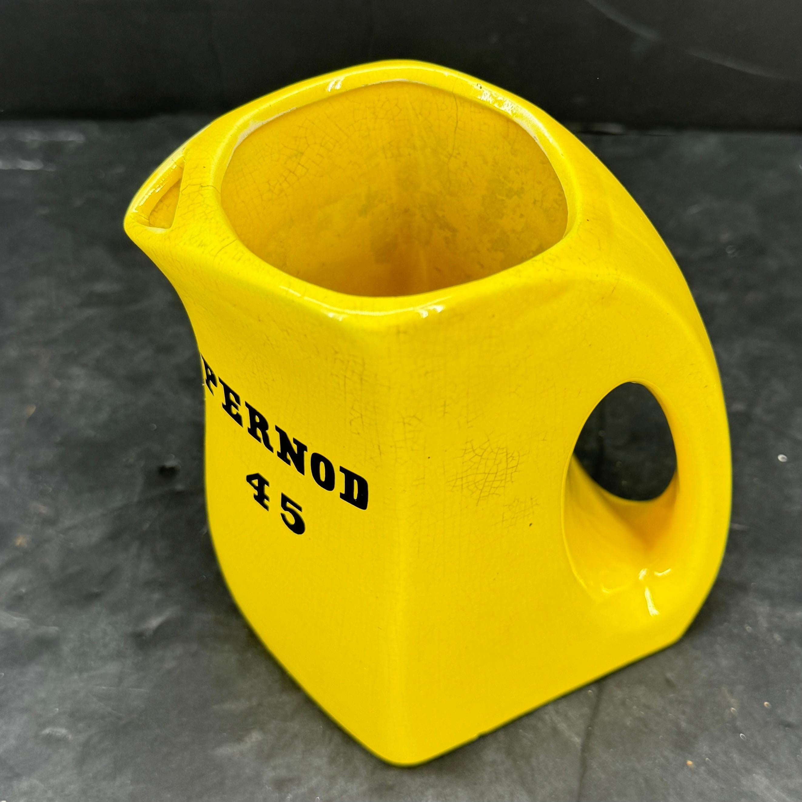 Charmant pichet vintage en céramique jaune Pernod 45. Cette pièce serait superbement exposée sur une étagère ou utilisée comme ustensile de bar dans un bar ou un restaurant de style classique ou moderne du milieu du siècle. Marqué Julius Wile Sons &