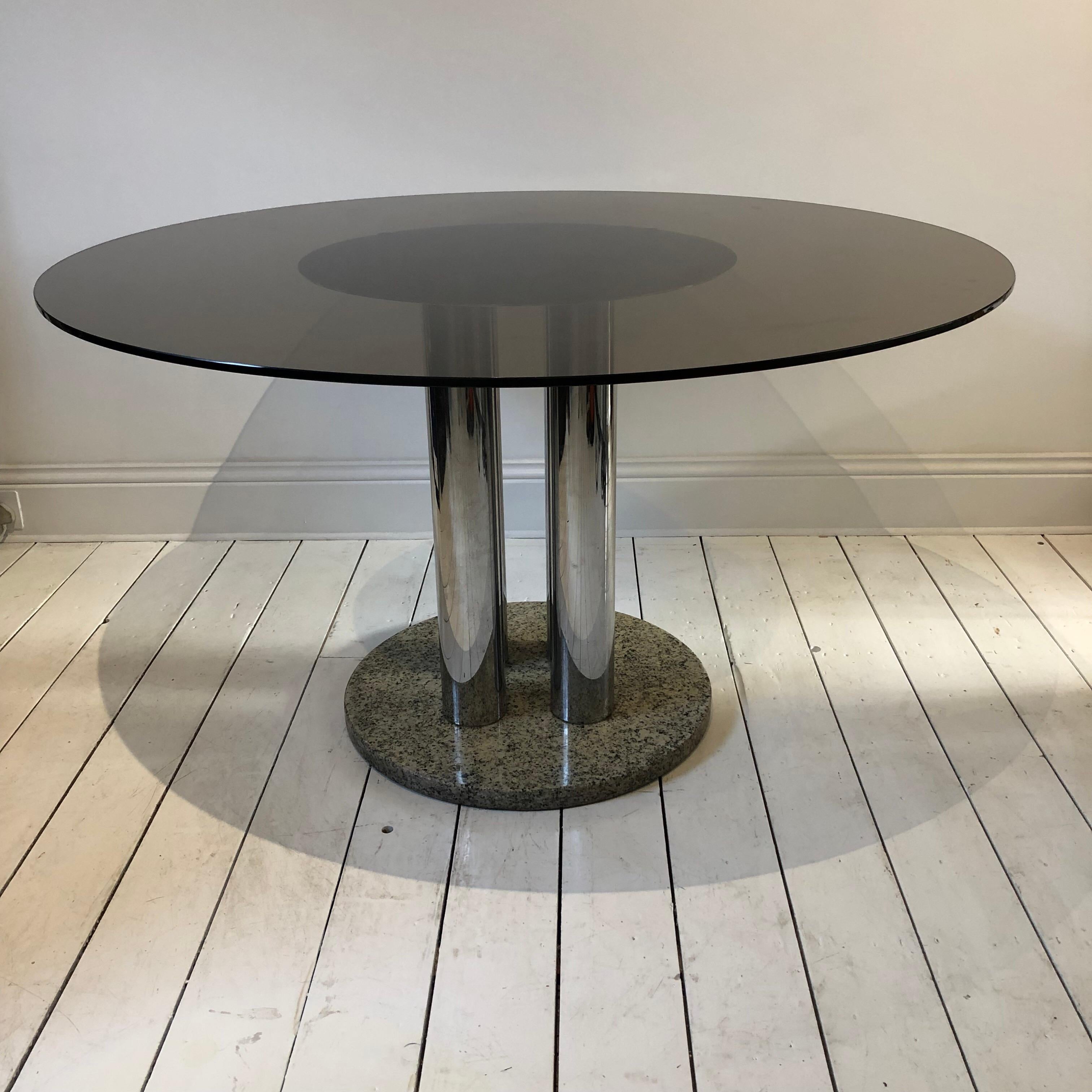 1970s Italian round dining table attributed to Marco Zanuso for Zanotta. Granite round base with four chrome pillar columns with a round chrome disk where the smoked glass top sits.
Overall very good condition with some wear or chips. The granite