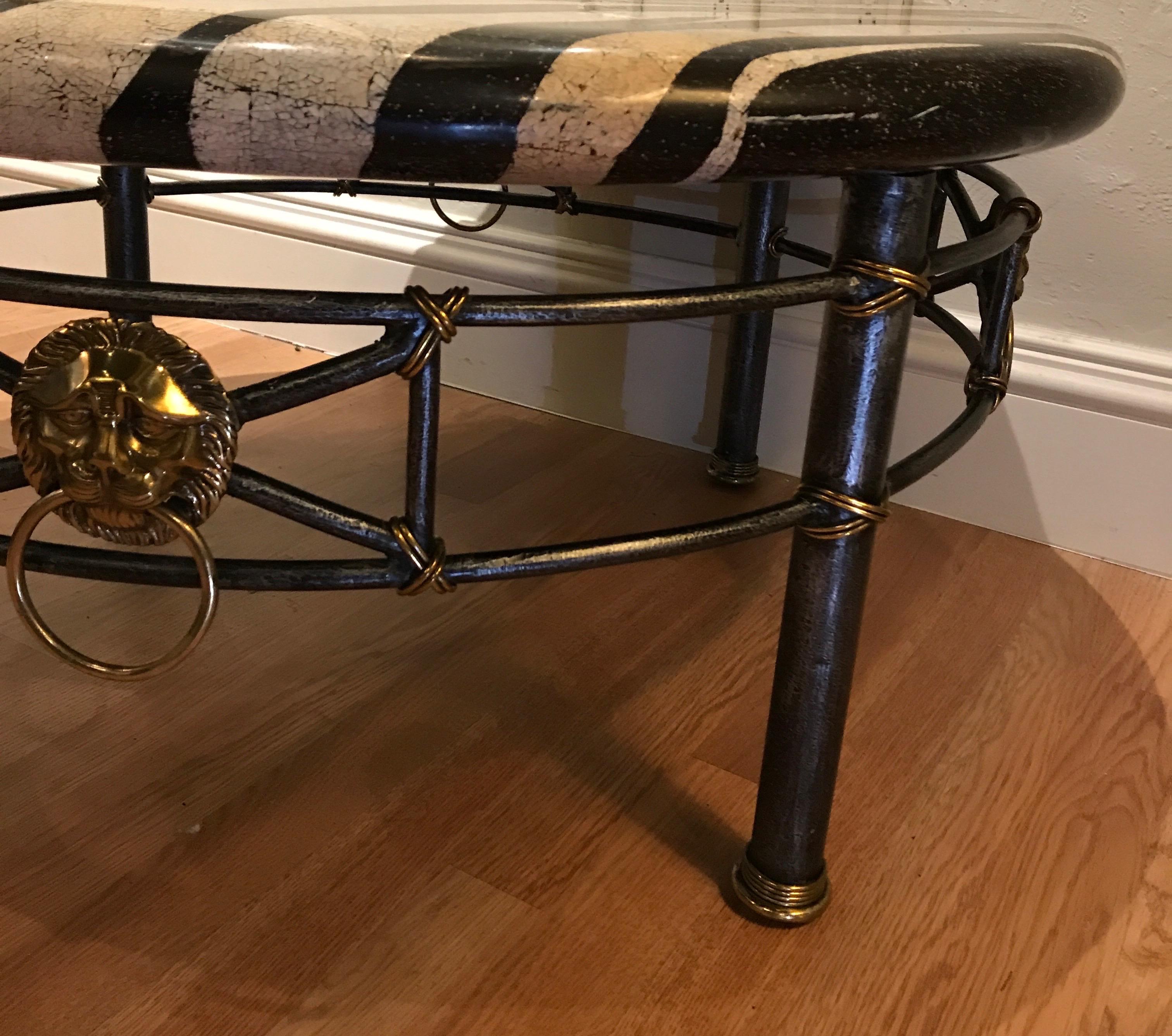 Midcentury coffee table with iron and brass base. Top is a zebra pattern
composite stone and sides are adorned with large lion heads with rings.