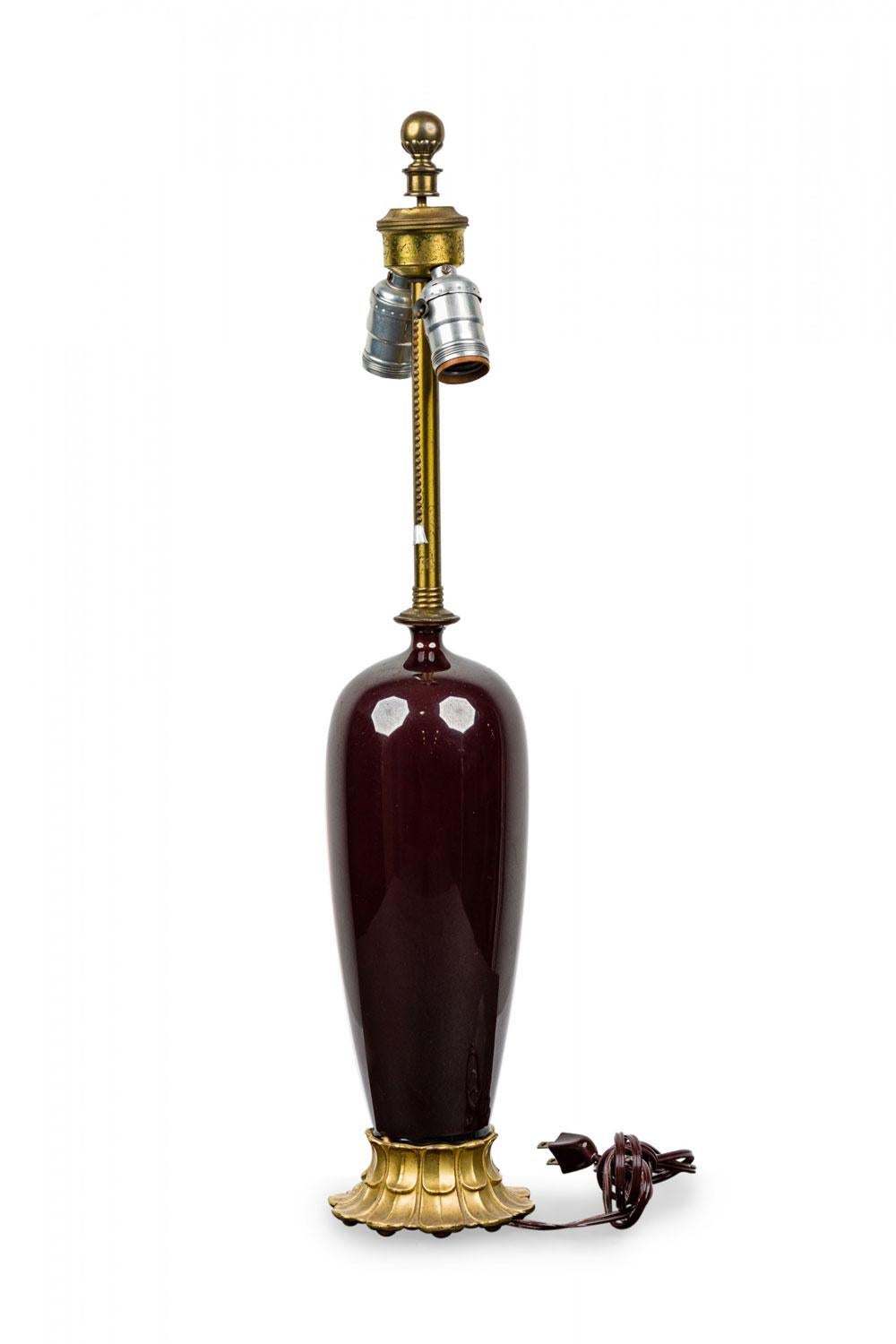 Lampe de table de style Mid-Centuy avec un corps en verre rouge sang-de-bœuf en forme de vase arrondi, monté sur une base en laiton feuillagé et muni d'une quincaillerie en laiton.

Livré sans abat-jour.