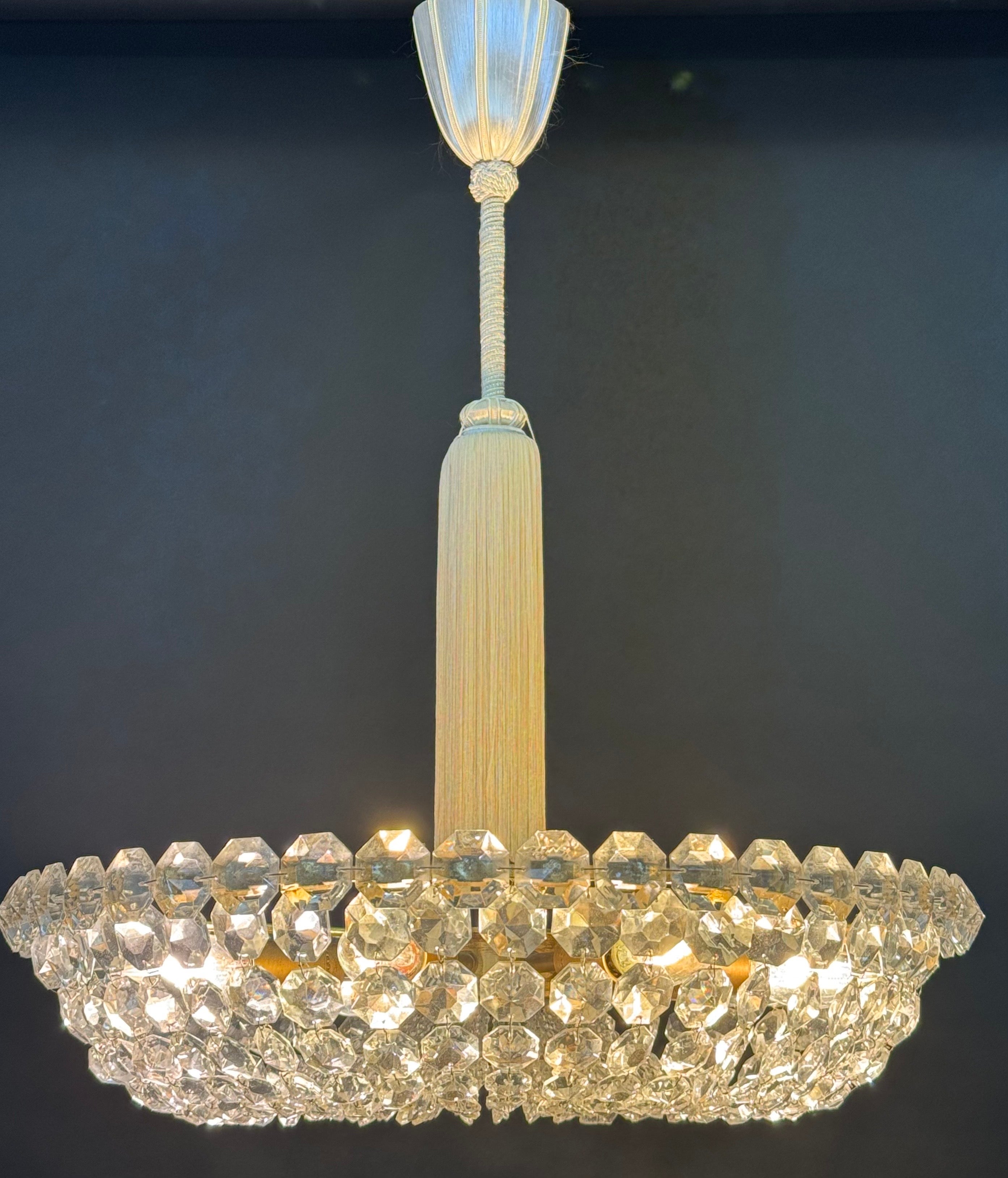 Cet exquis lustre Eleg est un exemple frappant de l'artisanat autrichien raffiné, alliant opulence et élégance intemporelle. Le cadre circulaire est méticuleusement orné de prismes de cristal à multiples facettes, créant un éblouissant spectacle de