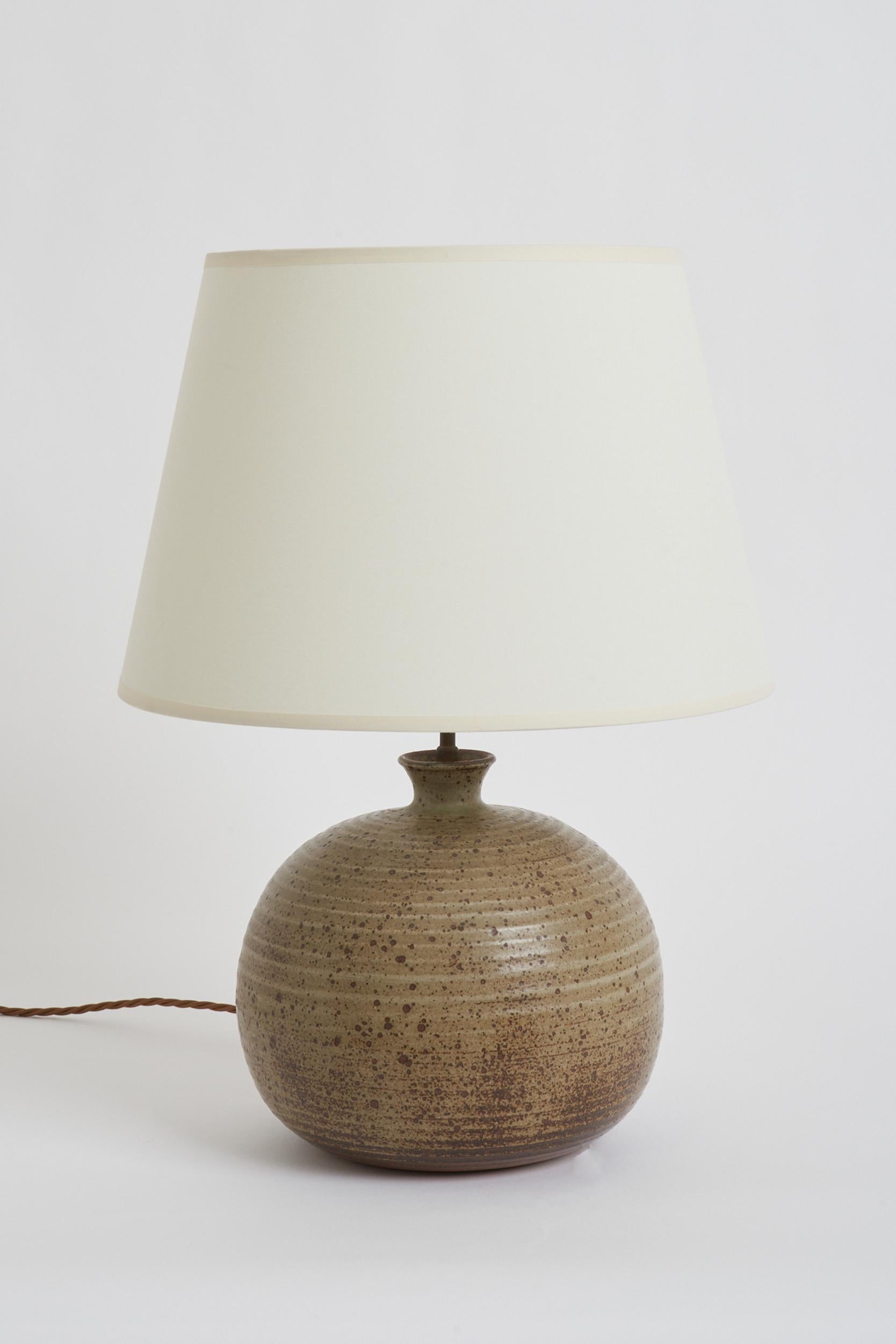 A mottled stoneware table lamp.
France, 1960s.
With the shade: 50 cm high by 35.5 cm diameter
Lamp base only: 31 cm high by 22 cm diameter.