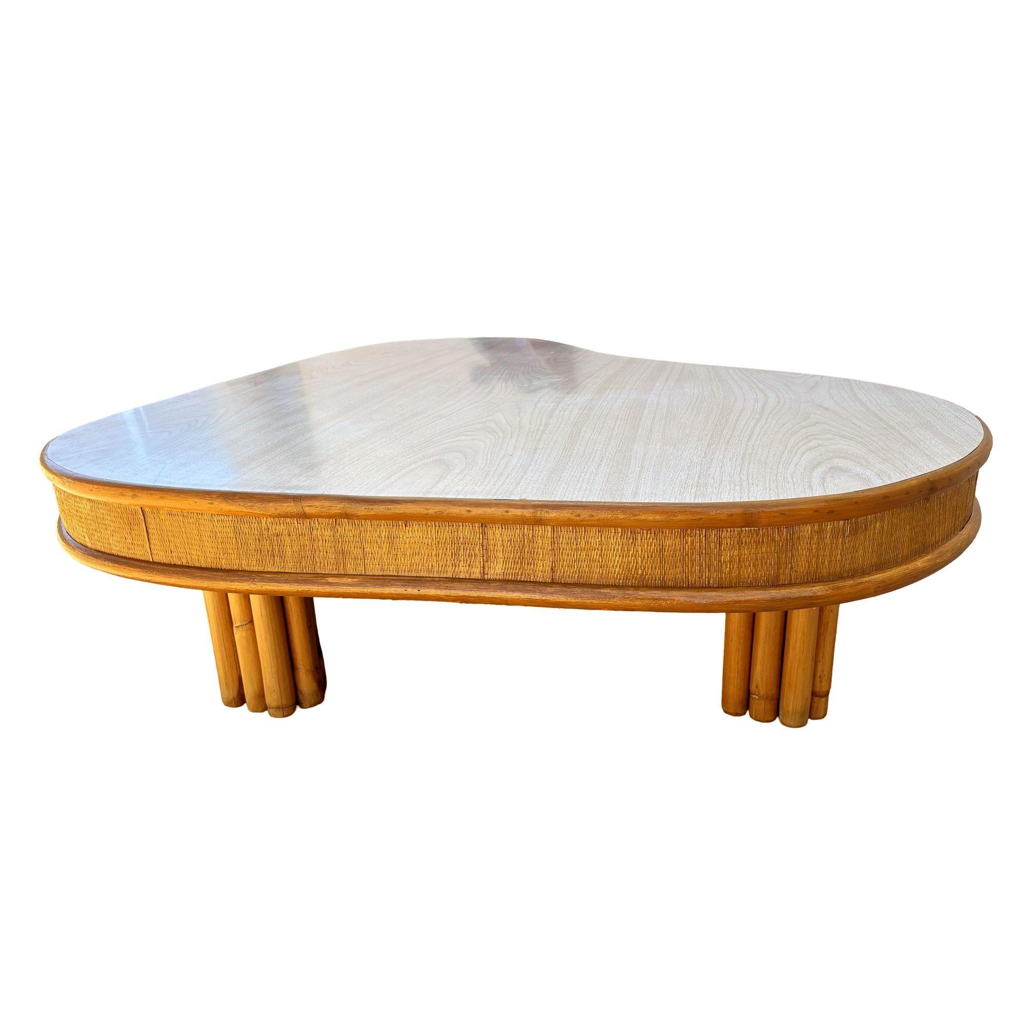 Cette table basse biomorphique en rotin et Formica du milieu du siècle, inspirée par Paul Frankl et magnifiquement restaurée, présente une bordure surdimensionnée en gazon et des pieds en rotin empilés verticalement. Il se compose d'un plateau de