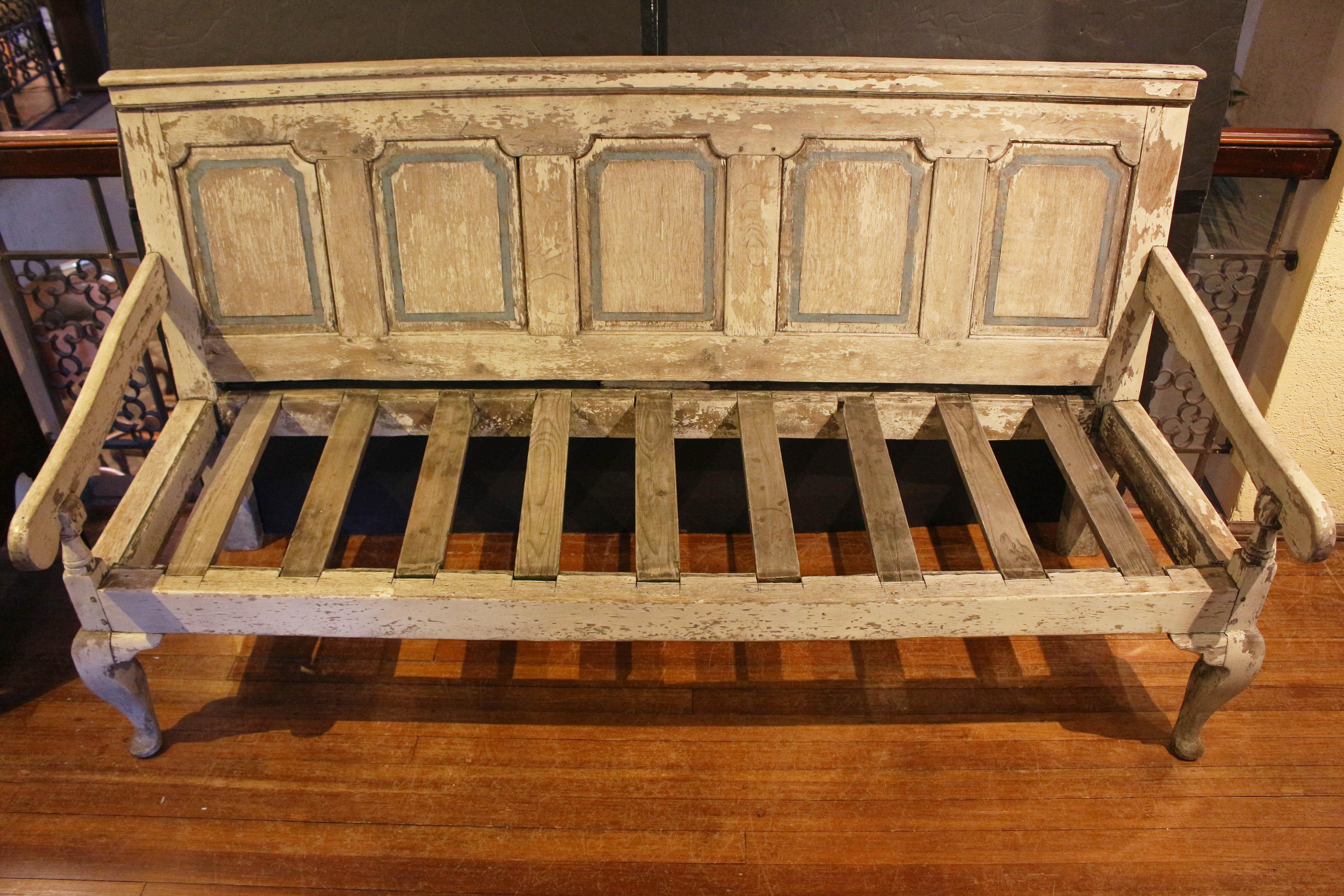 Mid-late 18th century English painted settle. In very old paint - cream to grey with blue accents - expected losses & peeling. Large, comfortable, removable cushion. Cabriole legs ending in pad feet. Shaped arms. Quintette of floating tombstone