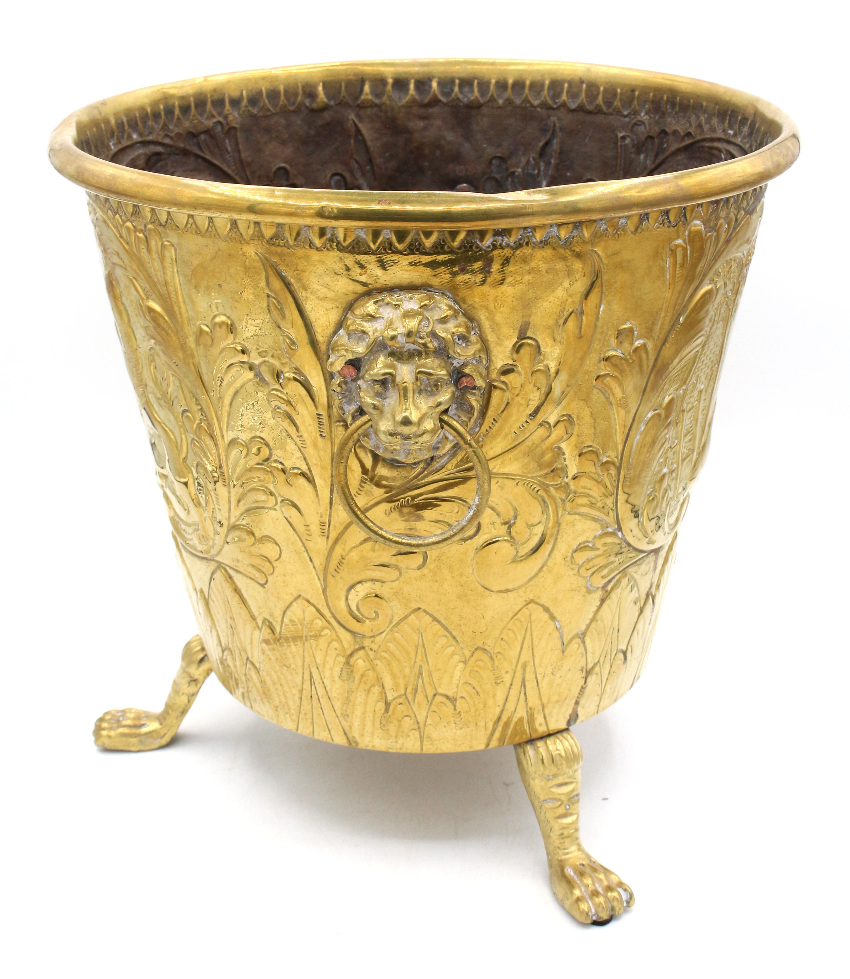 Mid-late 19th century brass jardiniere, Dutch. Bold lion masks with ring handles & tall lion leg & paw feet. Exuberantly decorated with hand worked repousse of a bold armorial crest (rampant lions flank a shield) reversing to a bucolic farm &