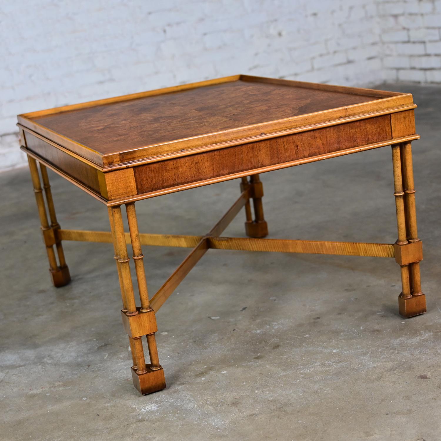 Handsome Mid-Late 20th Century Baker Furniture Campaign style rectangular end table comprised of walnut & mahogany veneer, burlwood top, triple cane faux bamboo legs, and X cross-stretcher. Beautiful condition, keeping in mind that this is vintage
