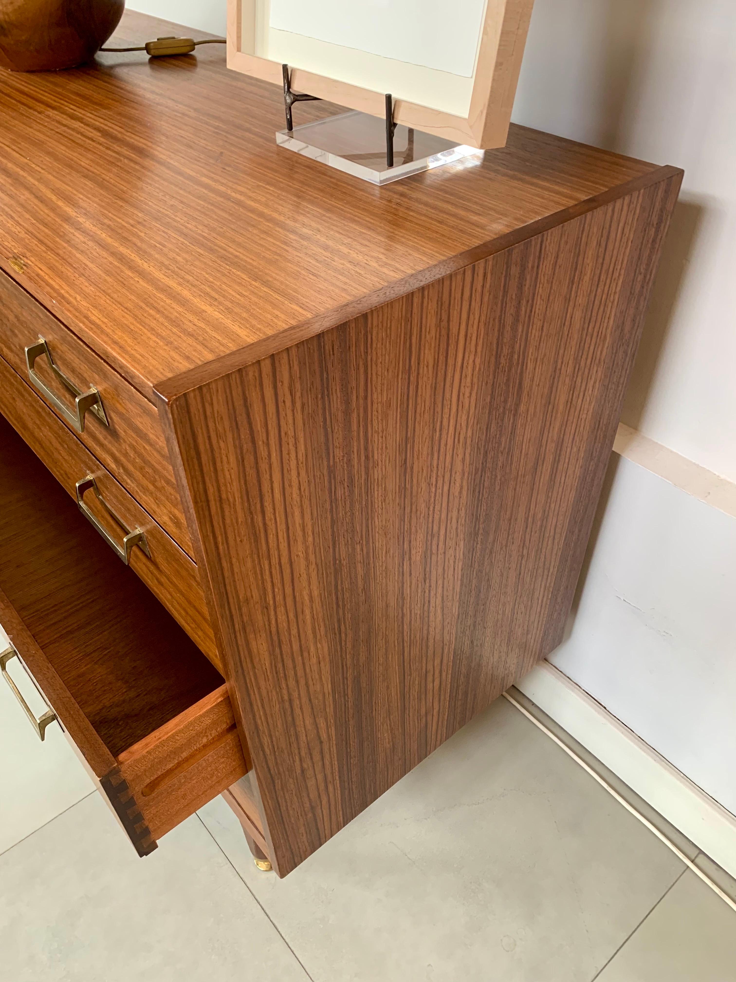 A beautiful and elegant chest of drawers from the 60s, in teak wood, with four drawers and bronze handles, the four legs also end with four rounded bronze sabots.