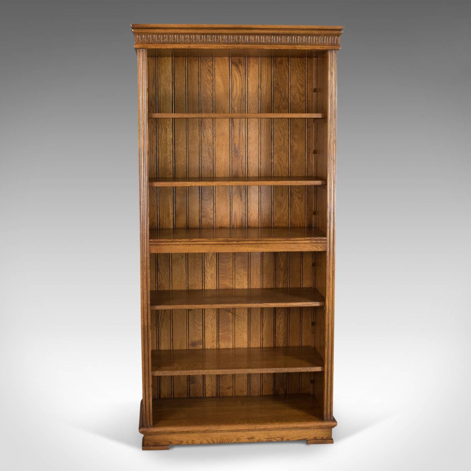 This is a mid-sized tall open bookcase with adjustable shelves in oak with gothic overtones dating to the late 20th century.

Oak with grain interest in the wax polished finish
Four adjustable shelves with one centre fixed shelf
Of quality