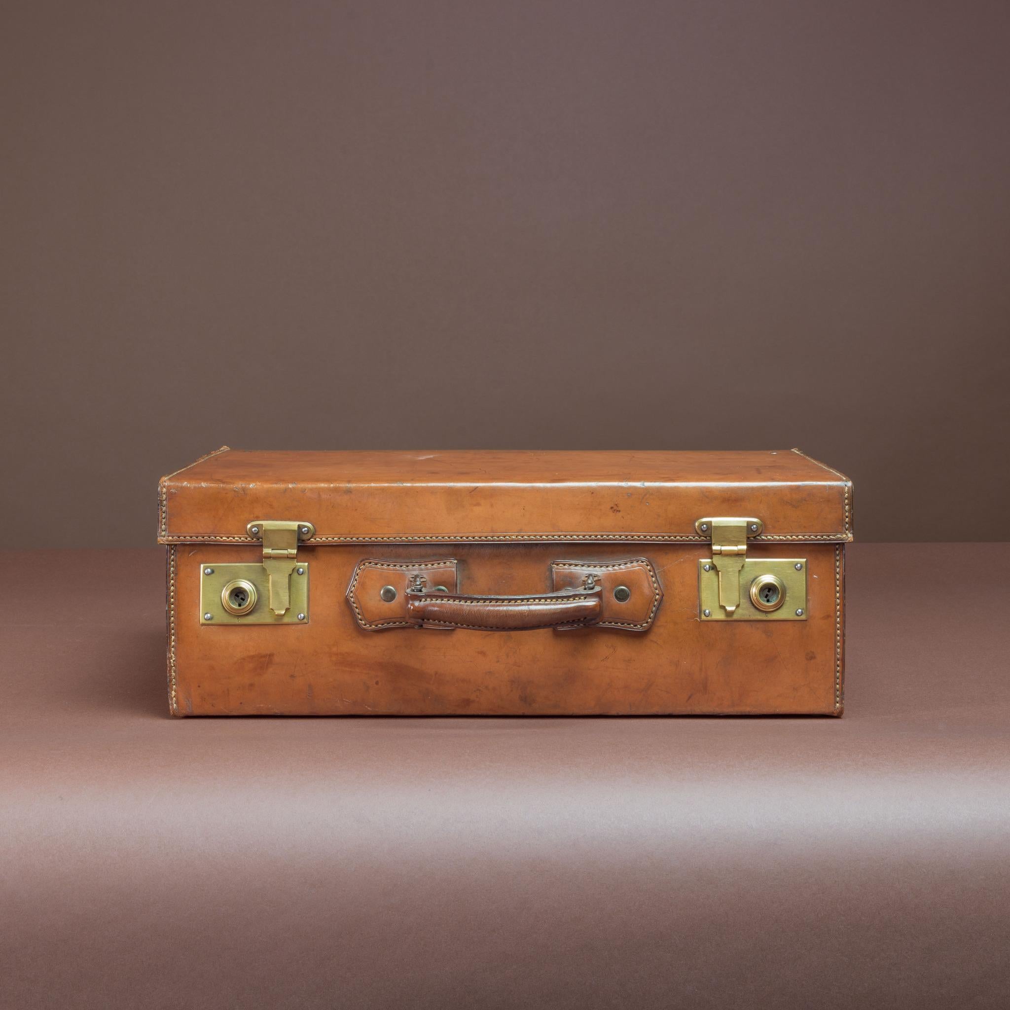 Attraente custodia in pelle, ideale per una notte o un weekend fuori casa. Ha una maniglia robusta, fermi in ottone, fodera in tessuto rifoderata all'interno e, cosa insolita, non ha iniziali. Circa 1930.

Dimensioni: 51,5 cm/20⅛ pollici (larghezza)