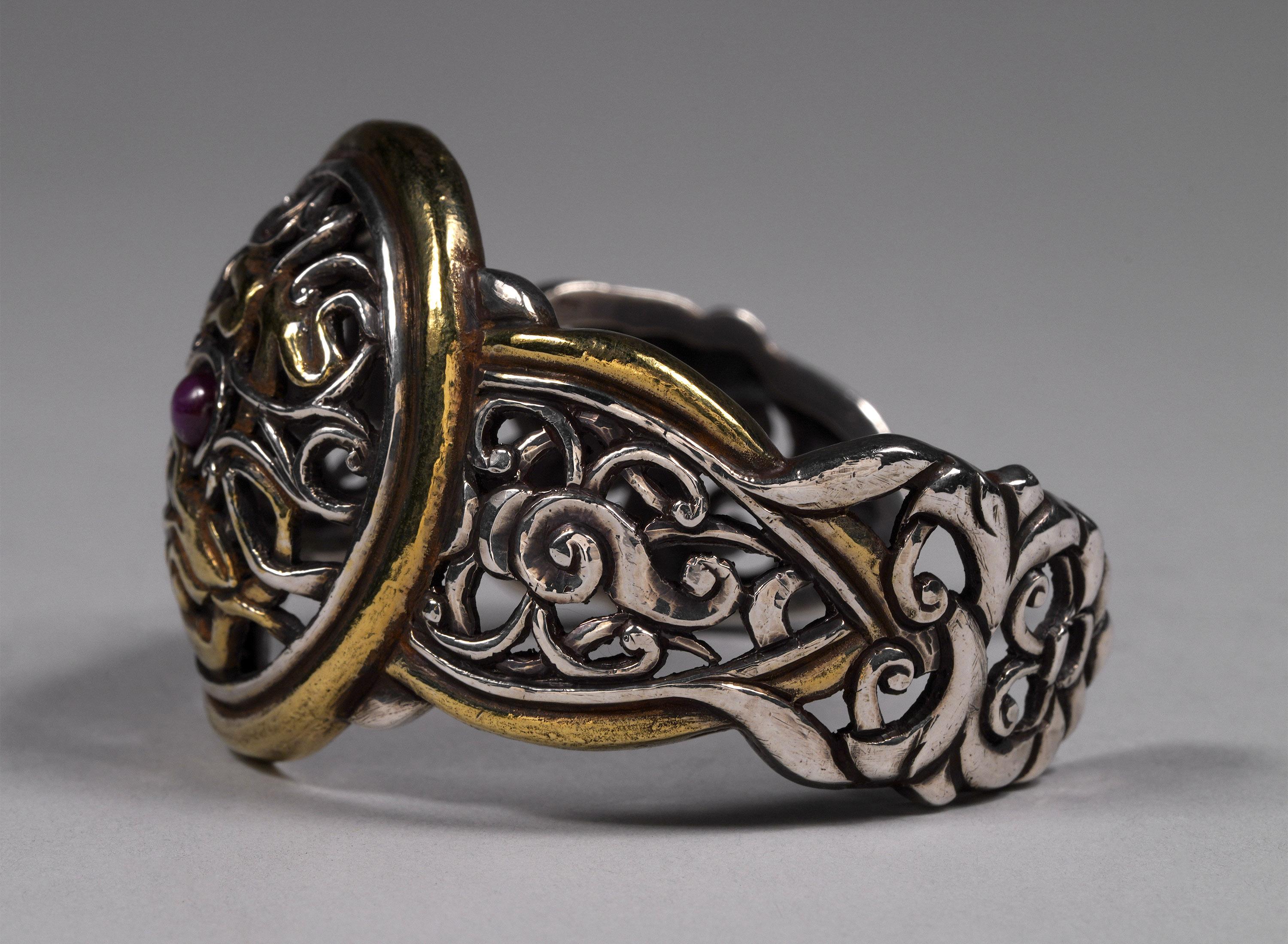 Mid to Late 20th Century Silver and Gold Plate Cuff Bracelet with Stylized Tibetan Motif

Cuff Bracelet of stylized Tibetan cloud motif with a central star ruby stone. The height is 1.75 inches, width is 2.75 inches and the interior circumference is