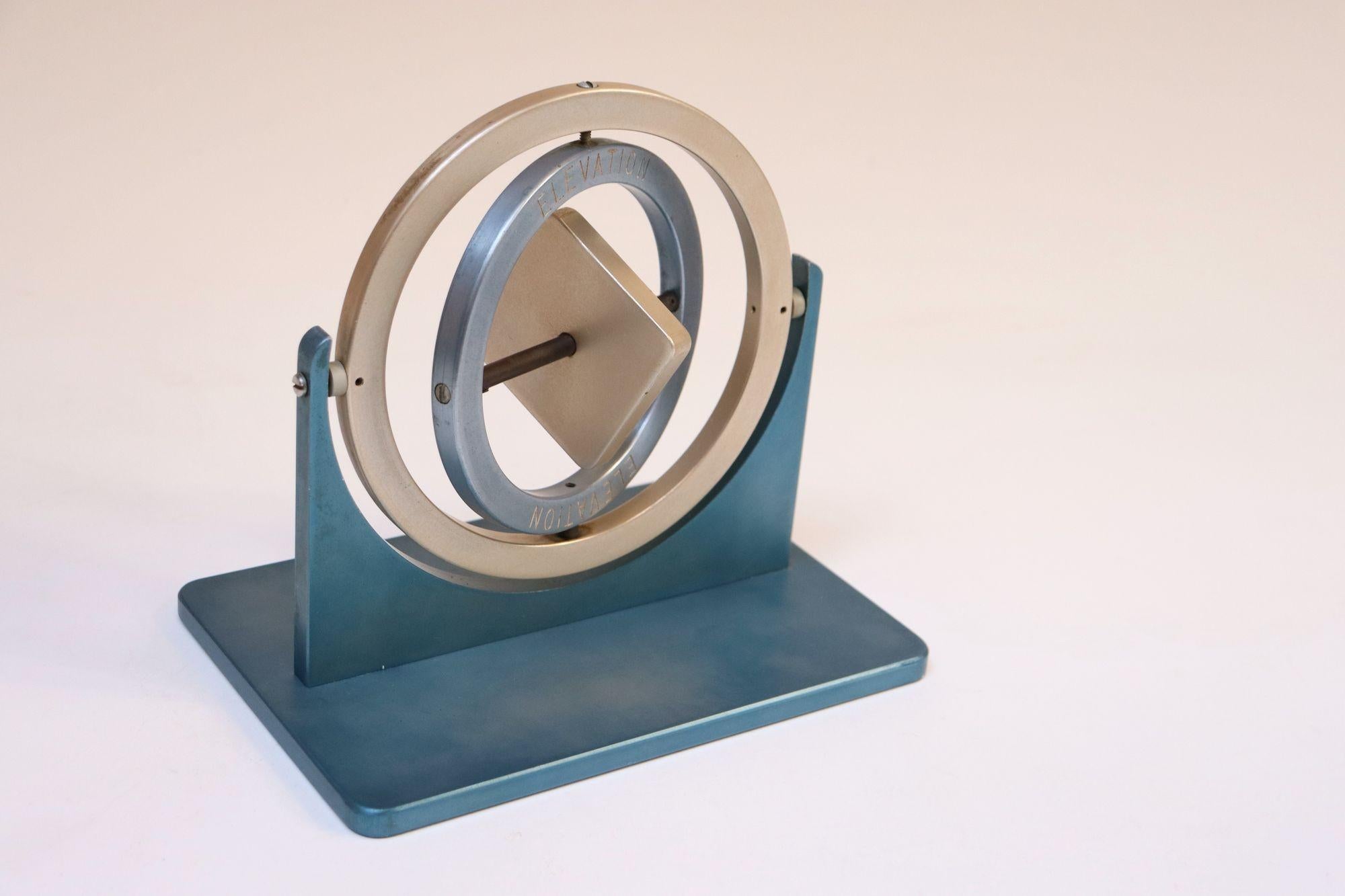 Gyroscope en aluminium anodisé bleu et argent, manipulé manuellement, composé de deux anneaux de cardan, d'un rotor central, d'un axe vertébral, d'un cadre et d'une base (vers la fin des années 1940/début des années 1950, États-Unis).
Dans ce cas,